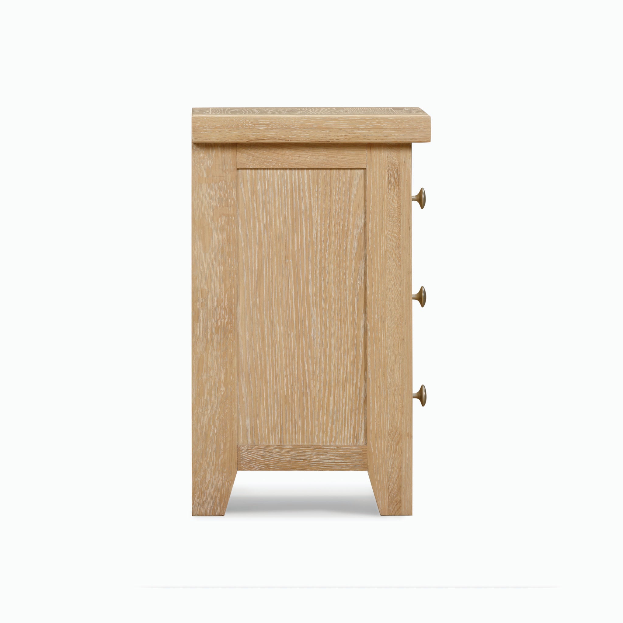 Side view of the Burford 3 Drawers Bedside Table in Natural Oak, showcasing a whitewash finish, three brass knobs on the right side, and a flat top surface.