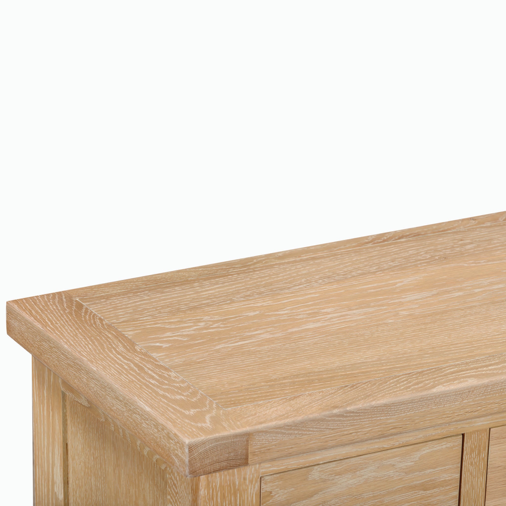 Close-up of a light-colored wooden table or dresser, resembling the smooth surface and edges of the Burford 3 Over 4 Chest of Drawers in Natural Oak, showcasing its rustic aesthetic.