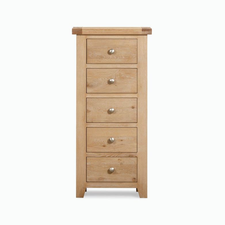 The Burford 5 Chest of Drawers in Natural Oak stands tall with its five drawers, each adorned with round metal knobs, set against a plain white background. This elegant piece offers practical storage solutions for any living space.