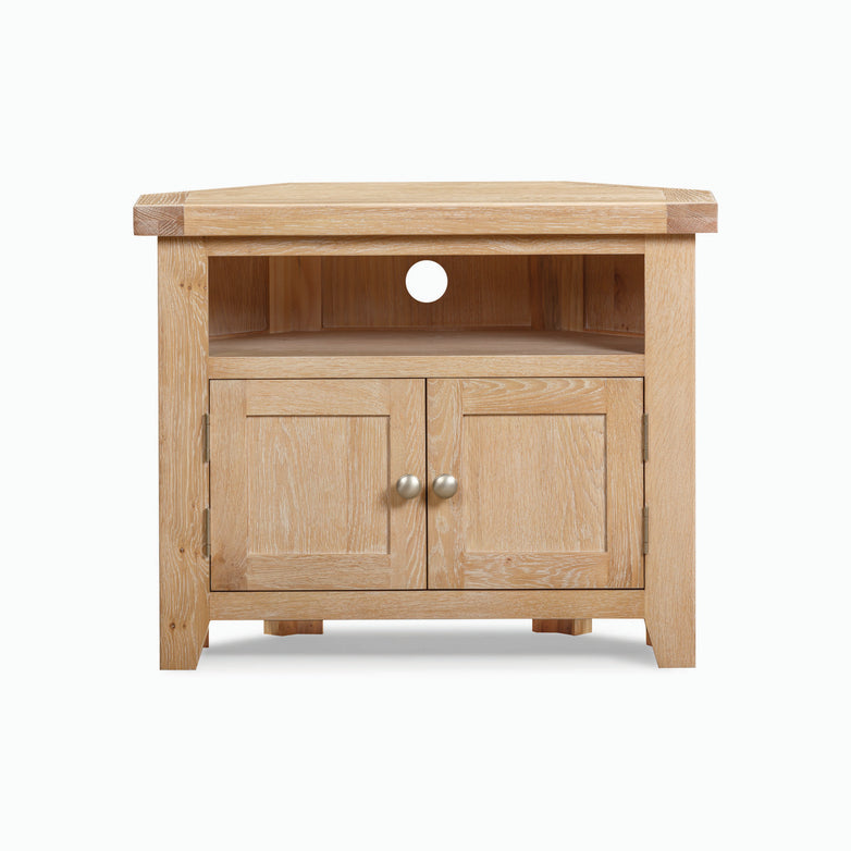 The Burford Corner Media Unit in Natural Oak is a wooden TV stand that features a shelf and two small doors beneath, exuding rustic charm and designed specifically for corner placement.