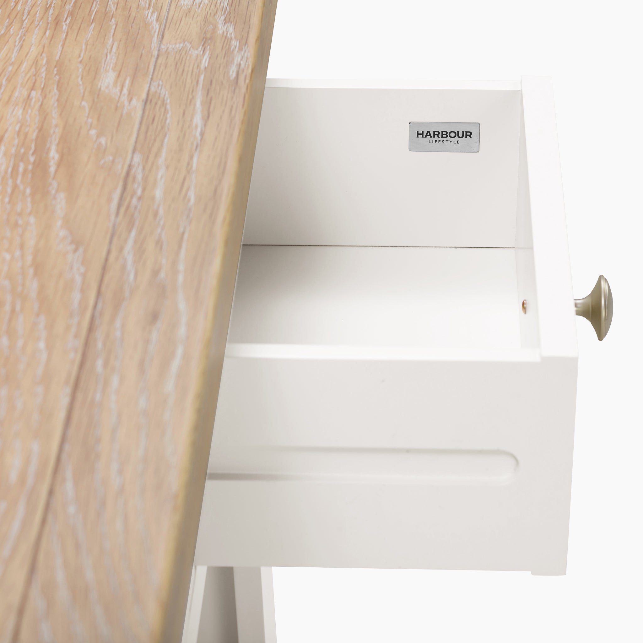 Open the white drawer of the Warm White Burford 2 Drawers Console Table, revealing a brand label inside.