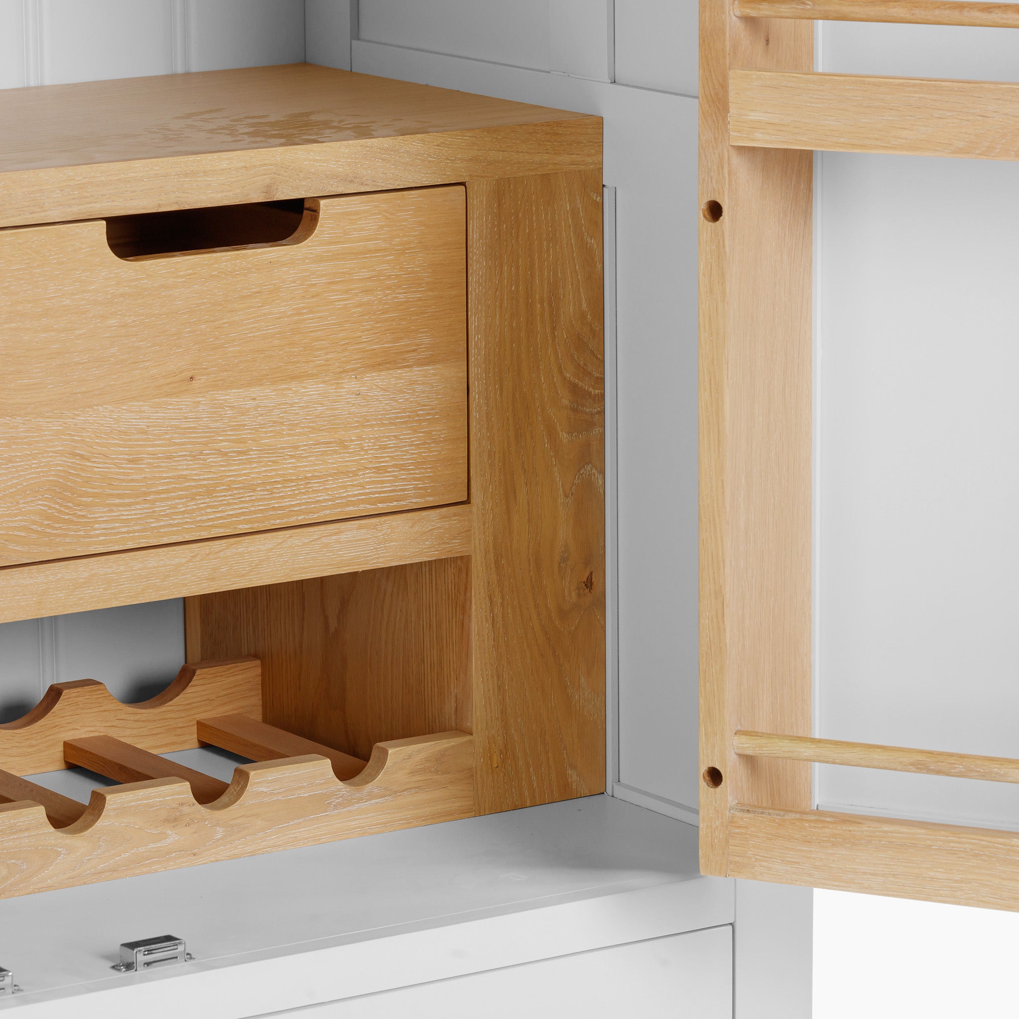 The Burford Double Larder Unit in Warm White, made from natural oak, includes a wooden cabinet with a drawer and wine rack, partially opened inside a white cupboard for seamless storage and organization.