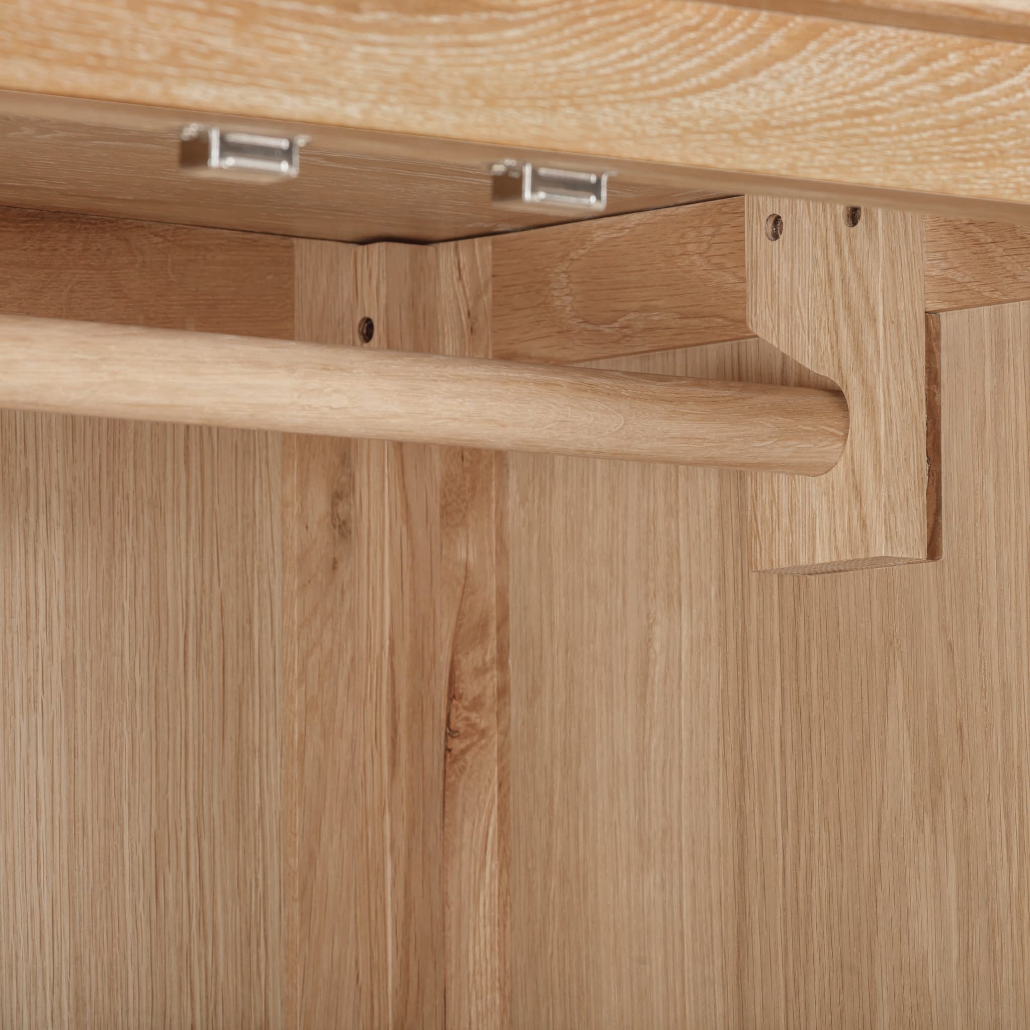 Close-up of the Burford Double Wardrobe with Drawer in Natural Oak, featuring a horizontal hanging rod and metal brackets under a wooden shelf, part of a solid oak furniture set.