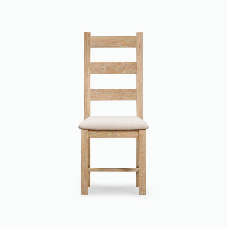 Front view of the Burford Ladderback Dining Chairs with Fabric Seat in Natural Oak, showcasing a padded light beige upholstered fabric seat and horizontal back slats.