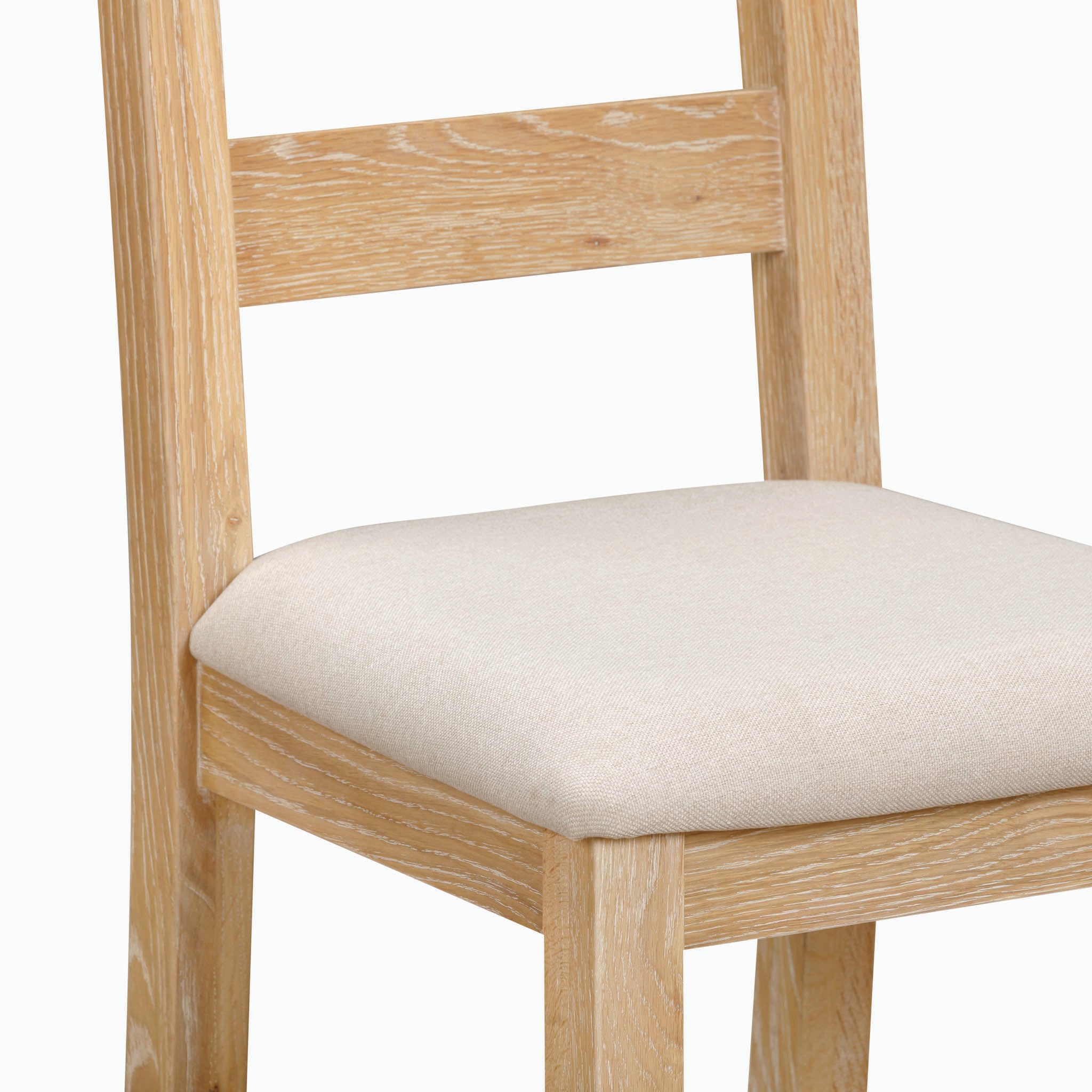 The Burford Ladderback Dining Chairs with Fabric Seat in Natural Oak, featuring a light-colored cushioned and upholstered fabric seat and backrest, are set against a plain background.