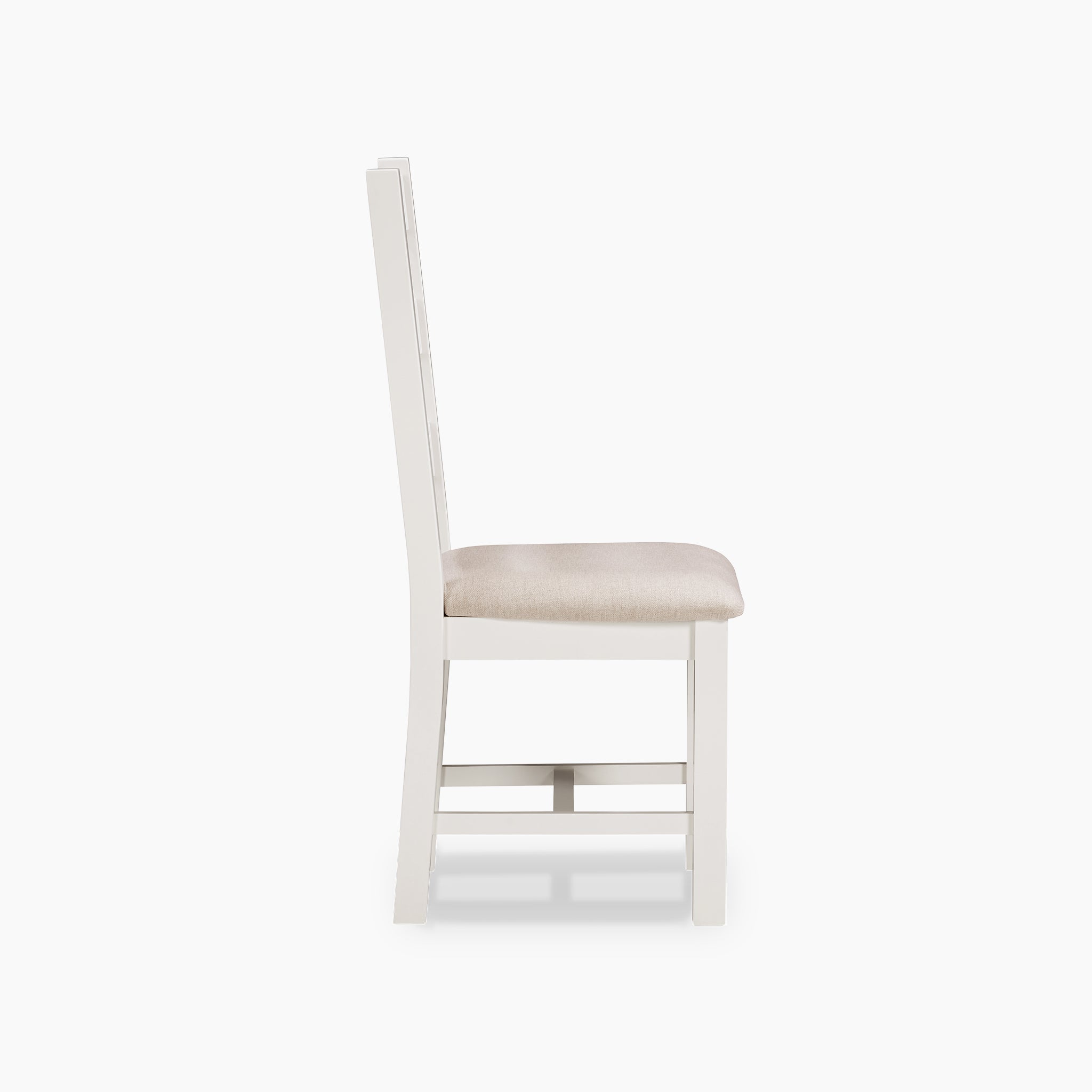 A side view of the Burford Set of 2 Ladderback Dining Chairs with Fabric Seat in Warm White highlights a white wooden frame and a beige cushioned seat, displayed against a white background.