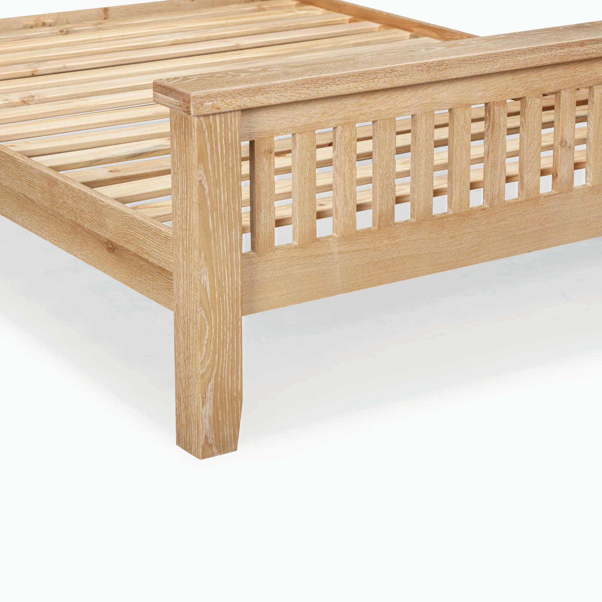 The Burford 5ft High-End Kingsize Bed Frame in Natural Oak is a light wooden bed that features a natural oak finish, complete with a slatted base and a headboard adorned with vertical slats. Plain white background.