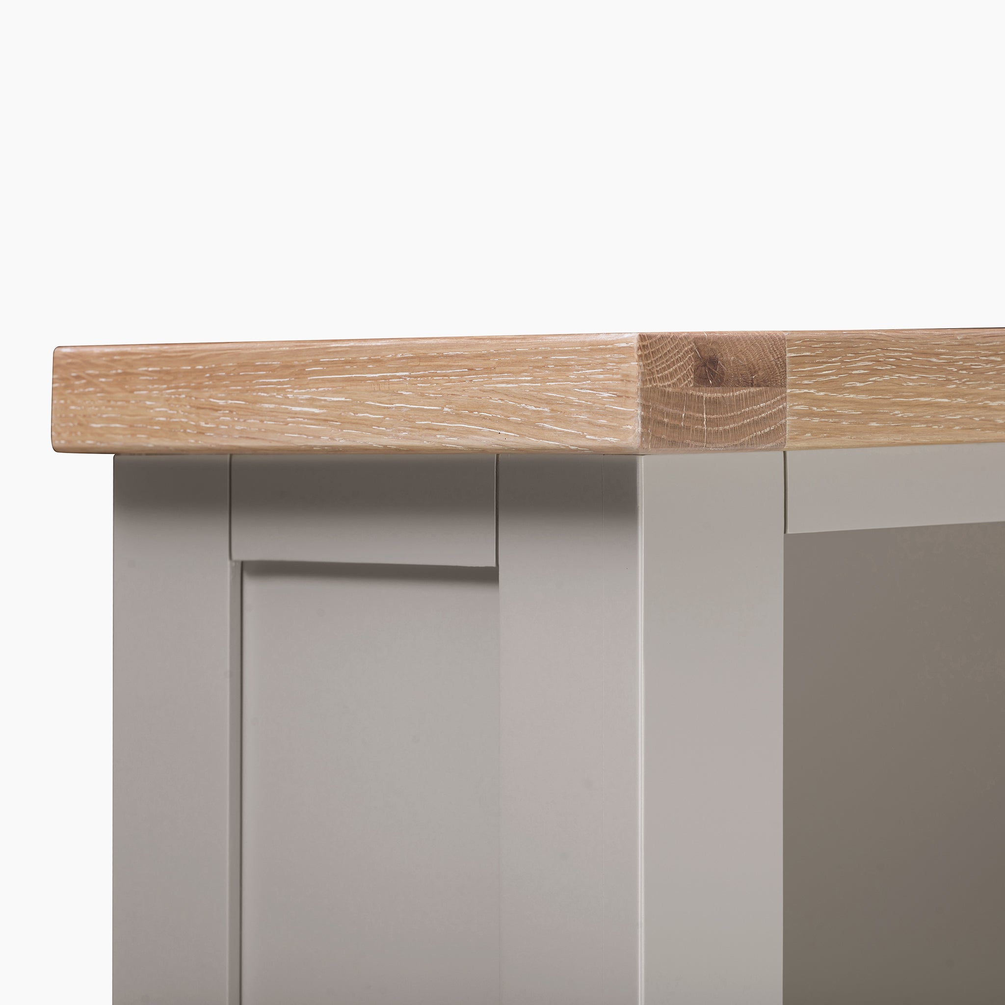 Close-up of a wooden table corner, featuring a natural oak top and a gray painted side, reminiscent of the stylish Burford Large Bookcase in Pebble Grey.