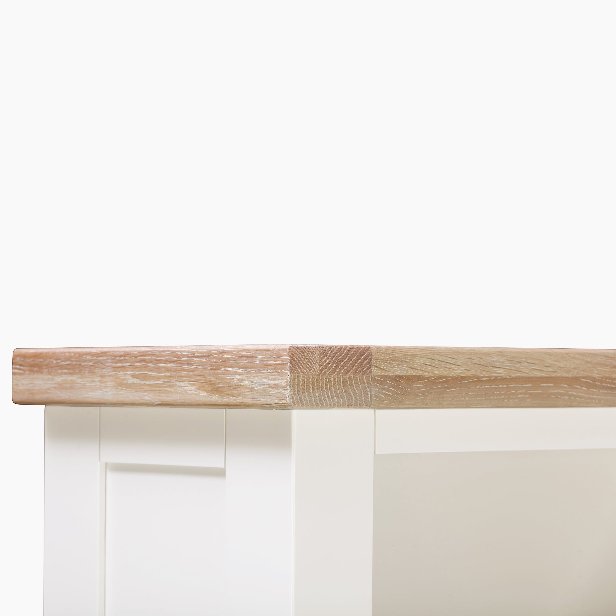 Close-up of a bookcase corner, featuring a white backdrop and shelves with a light wood grain finish reminiscent of natural oak.