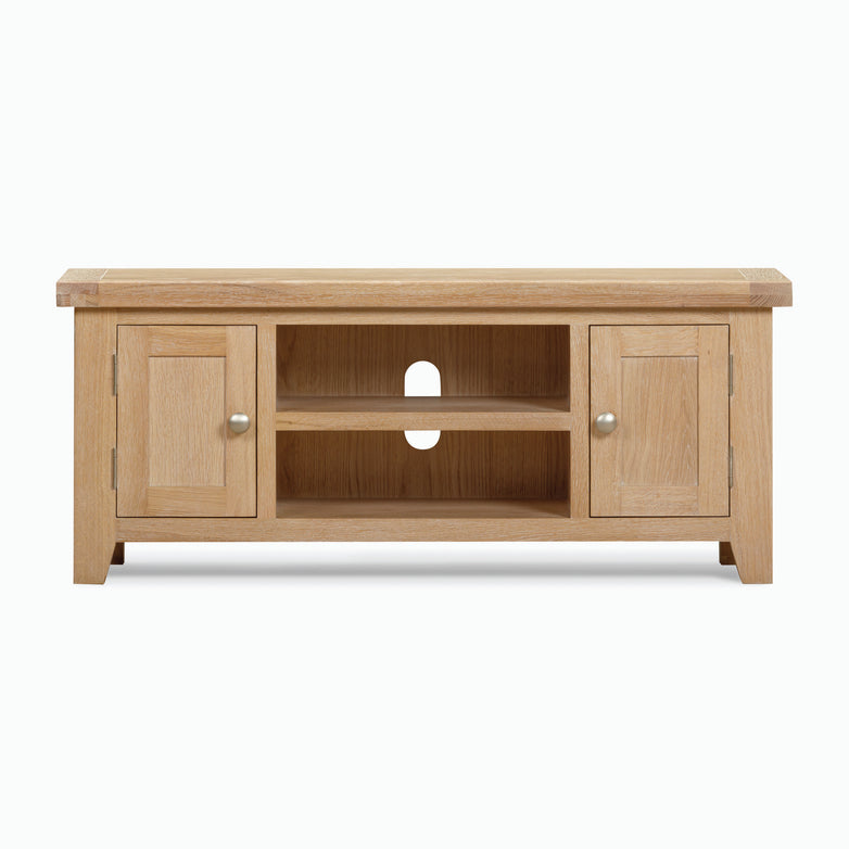 The Burford 120cm Media Unit in Natural Oak is a wooden TV stand featuring a natural oak finish, two cabinets on each side, two open shelves in the center, and a cable management hole.