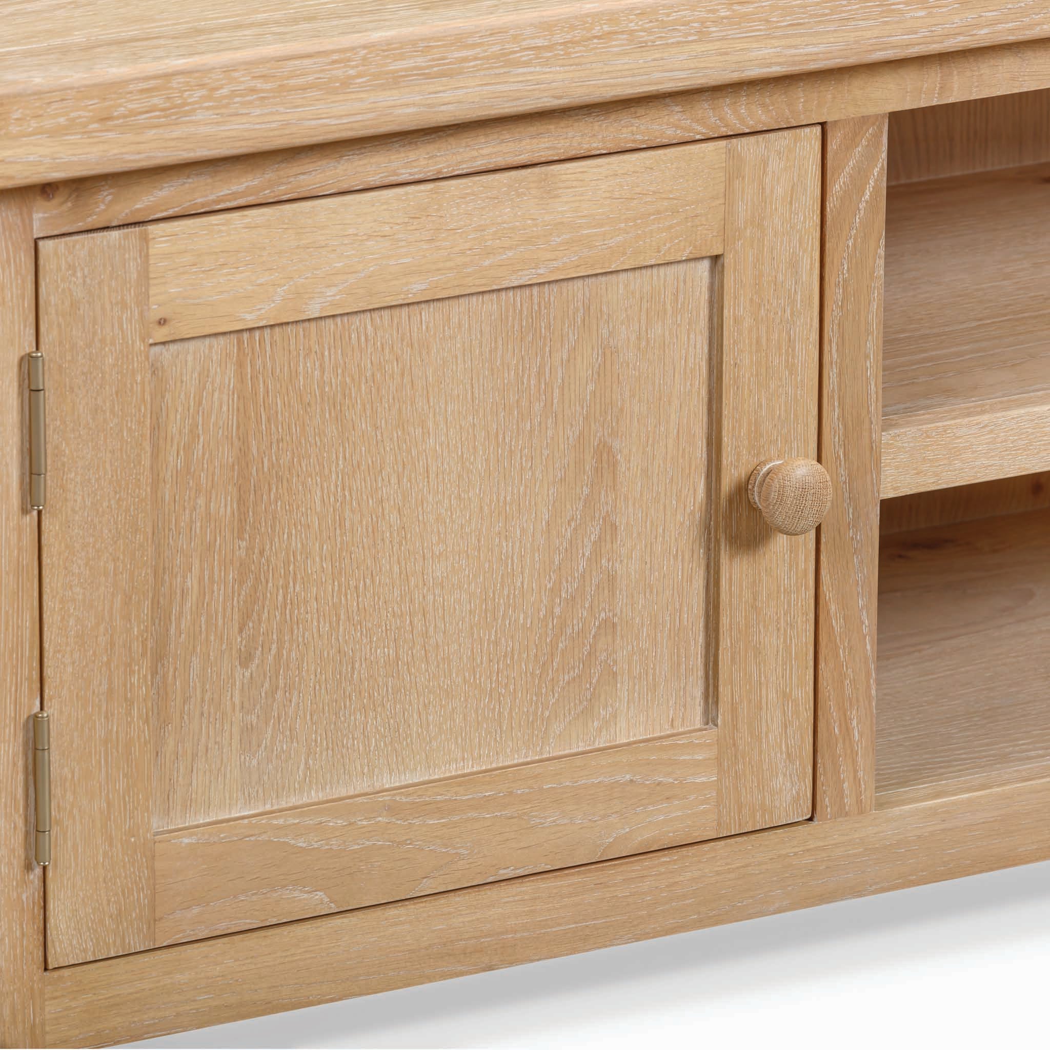 Close-up of a Burford 120cm Media Unit in Natural Oak, featuring a light wood cabinet door with a round knob and adjacent open shelves.