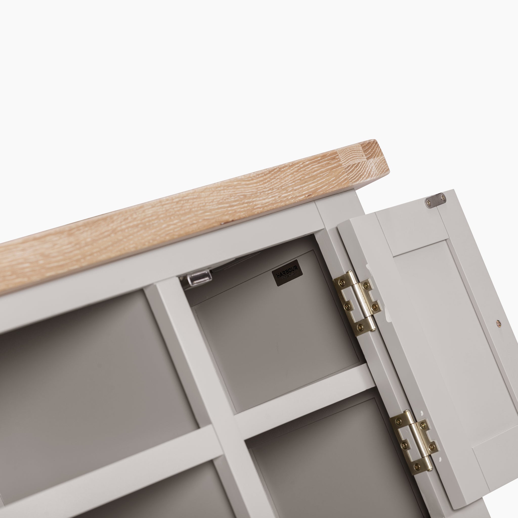 Close-up of a corner of the Burford 120cm Media Unit in Pebble Grey, featuring an open door that reveals the natural oak interior, along with visible hinges and a tag inside.