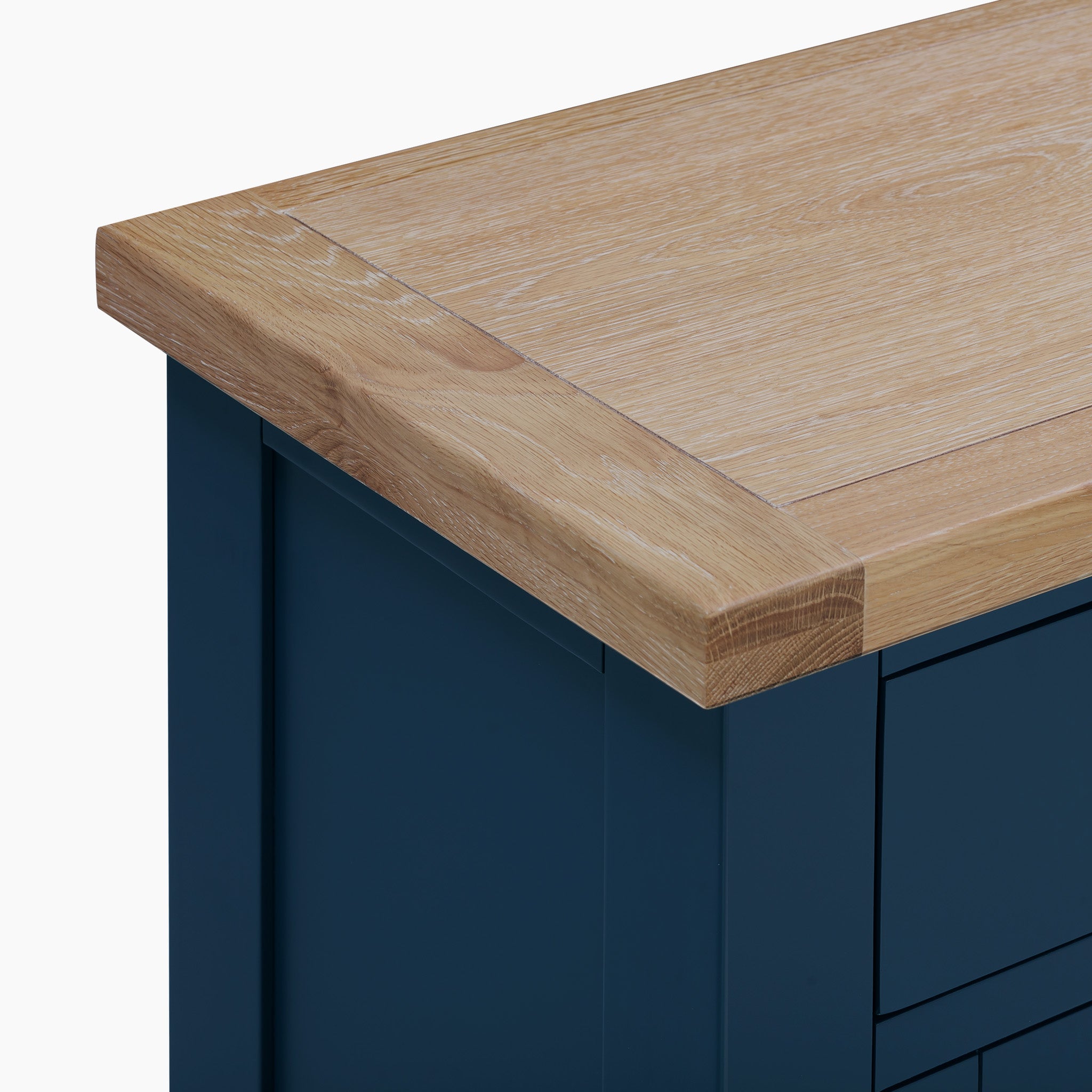 Close-up of a natural oak tabletop with a Navy Blue Burford 2 Door 2 Drawers Sideboard underneath.