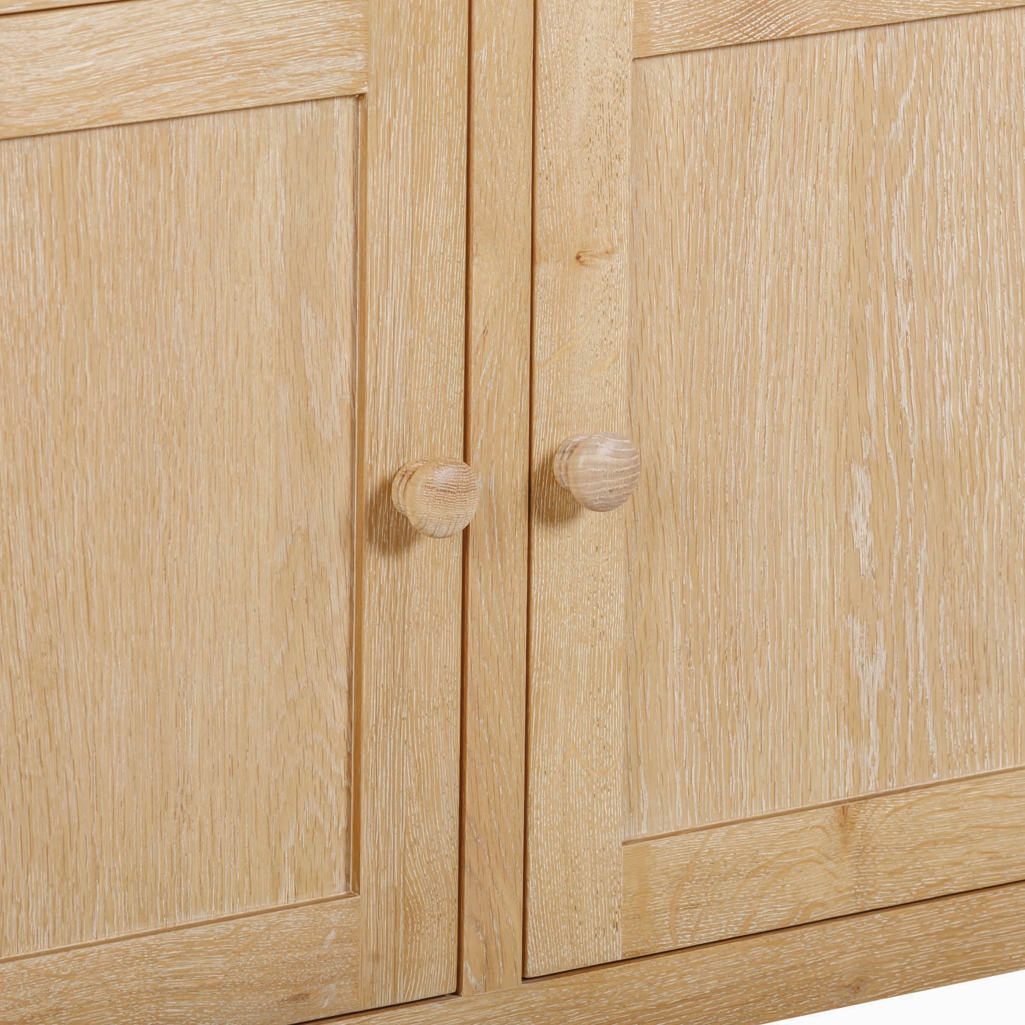 Close-up of a Burford 2 Door 2 Drawers Sideboard in Natural Oak, with two doors, each featuring a round wooden handle.