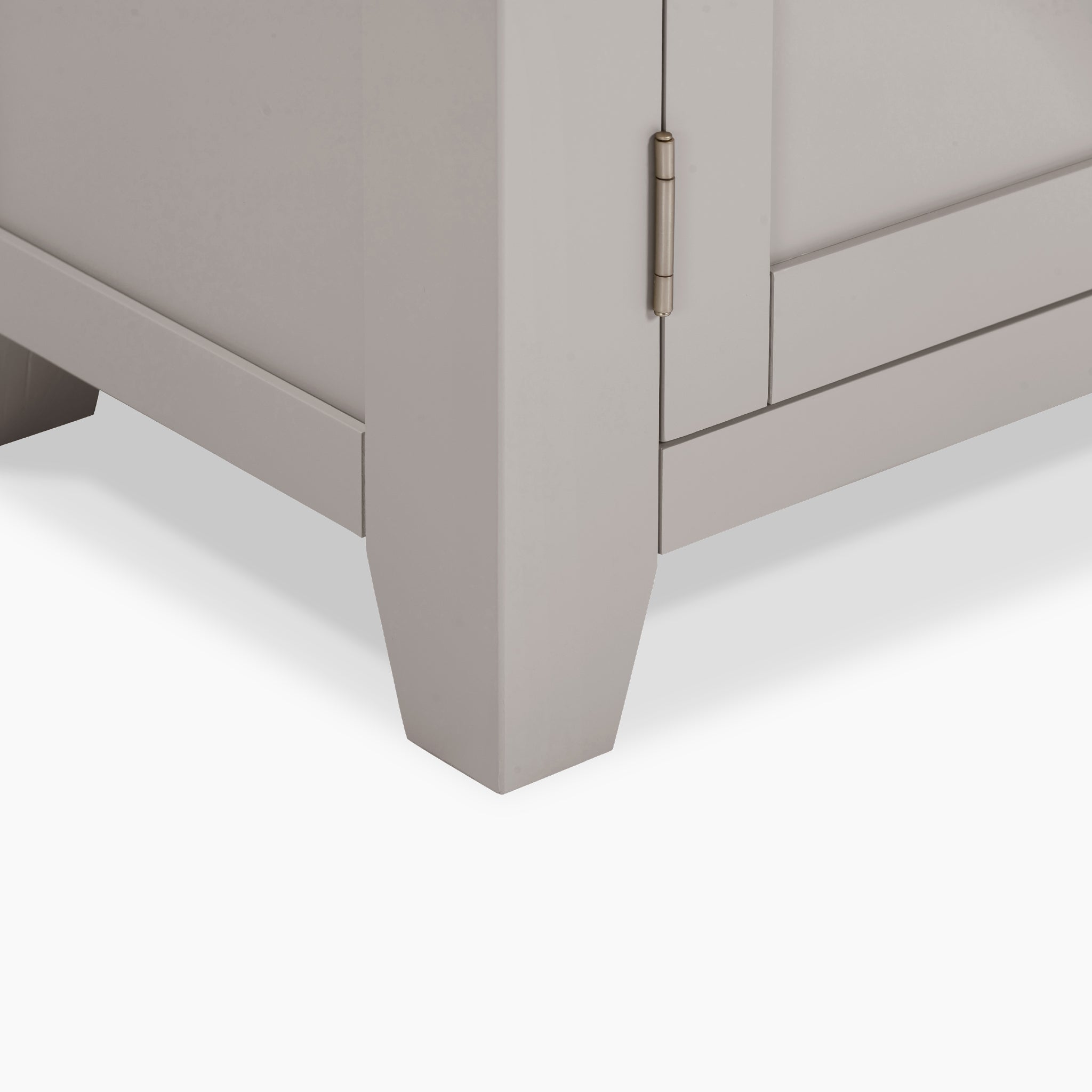 Close-up of a cabinet corner in Pebble Grey with a closed door, featuring a metal hinge and tapered legs, reminiscent of the design seen in the Burford 2 Door 2 Drawers Sideboard.