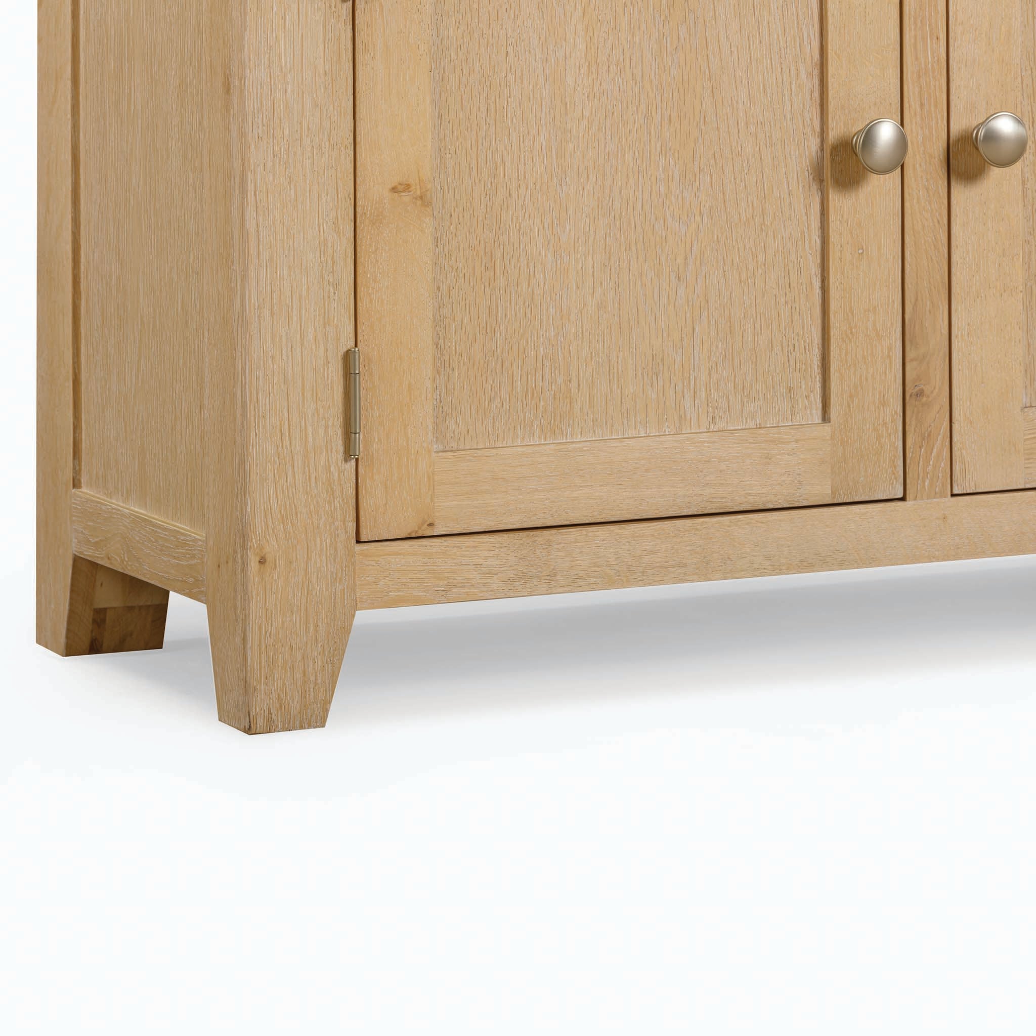 Close-up of the lower section of the Burford Large 3 Door 3 Drawers Sideboard in Natural Oak, with metal knobs, showcasing the natural oak wood grain and corner details, perfect for stylish storage.