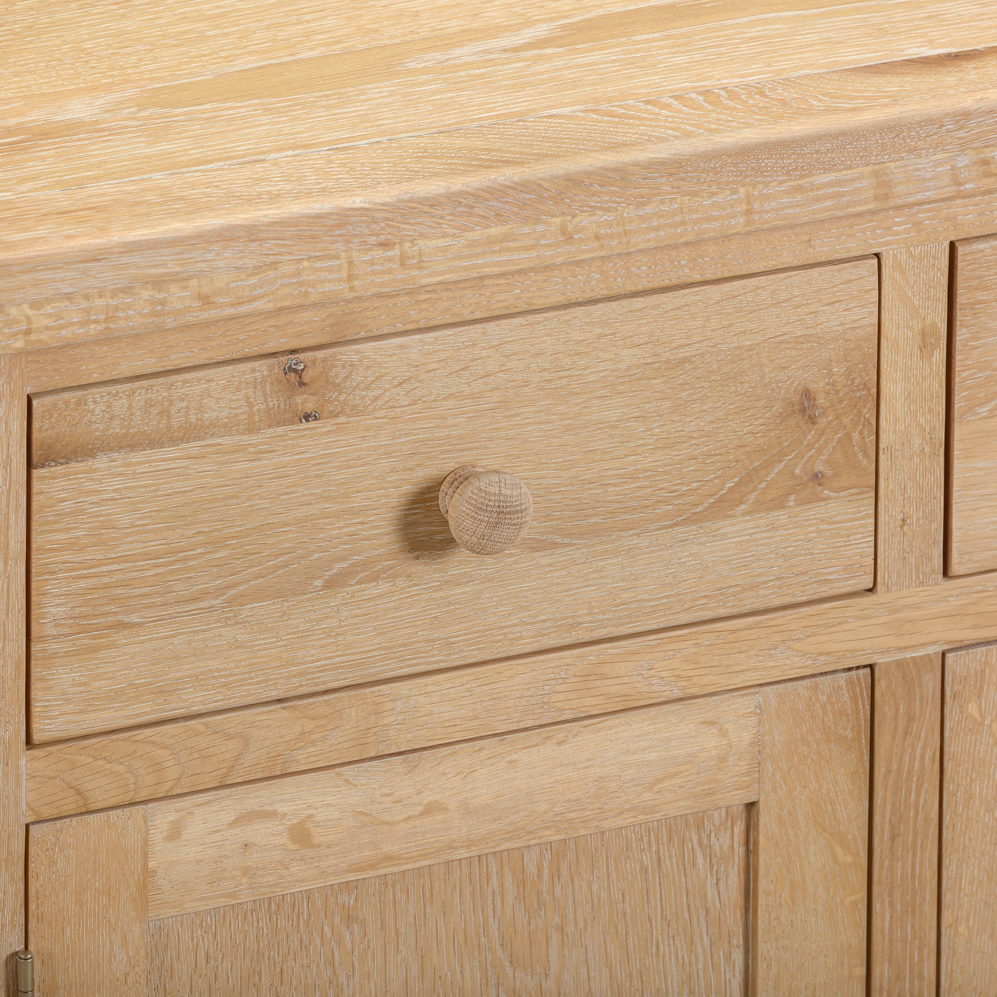 The Burford Large 3 Door 3 Drawers Sideboard in Natural Oak is perfect for additional storage in any room, featuring three spacious drawers with sleek wooden knobs and a natural oak wood grain finish.