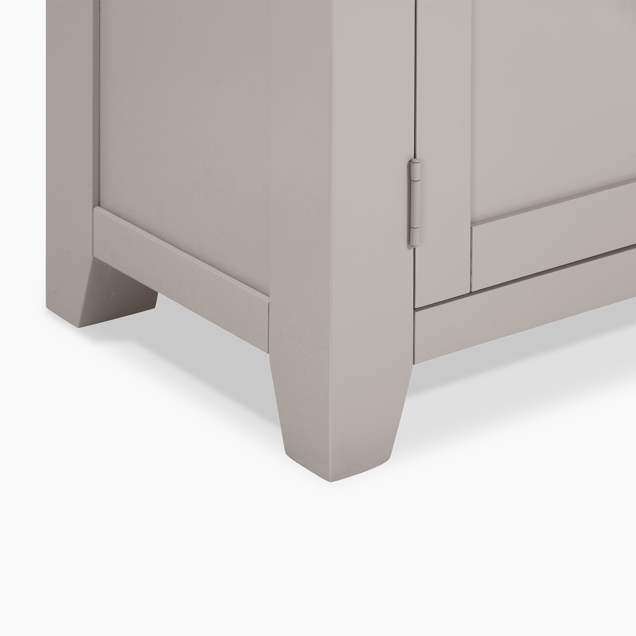 Close-up of the bottom corner of a Burford Large 3 Door 3 Drawers Sideboard in Pebble Grey, showcasing the leg and part of the door with a sturdy hinge.