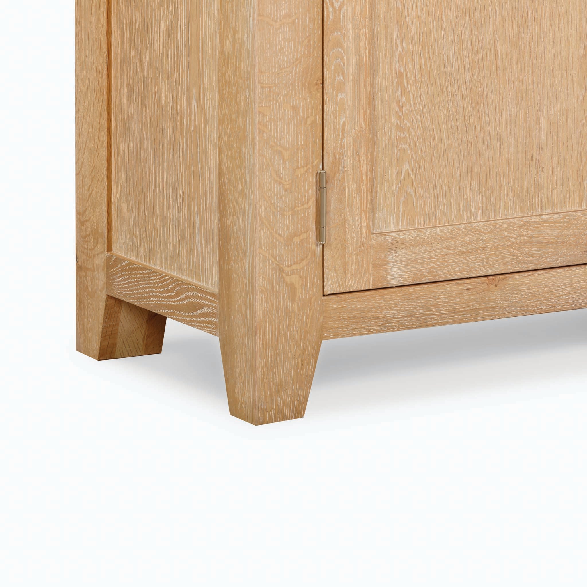 Close-up of a Burford Large 4 Door 3 Drawers Sideboard corner crafted from Natural Oak, featuring a visible hinge and door, highlighting its sturdy legs and detailed grain texture—an exemplary piece of storage furniture.