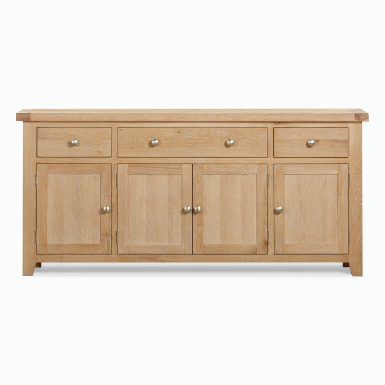 The Burford Large 4 Door 3 Drawers Sideboard in Natural Oak, featuring three top drawers and four bottom cabinets, all adorned with round metal knobs. This elegant piece of storage furniture combines functionality with timeless style.