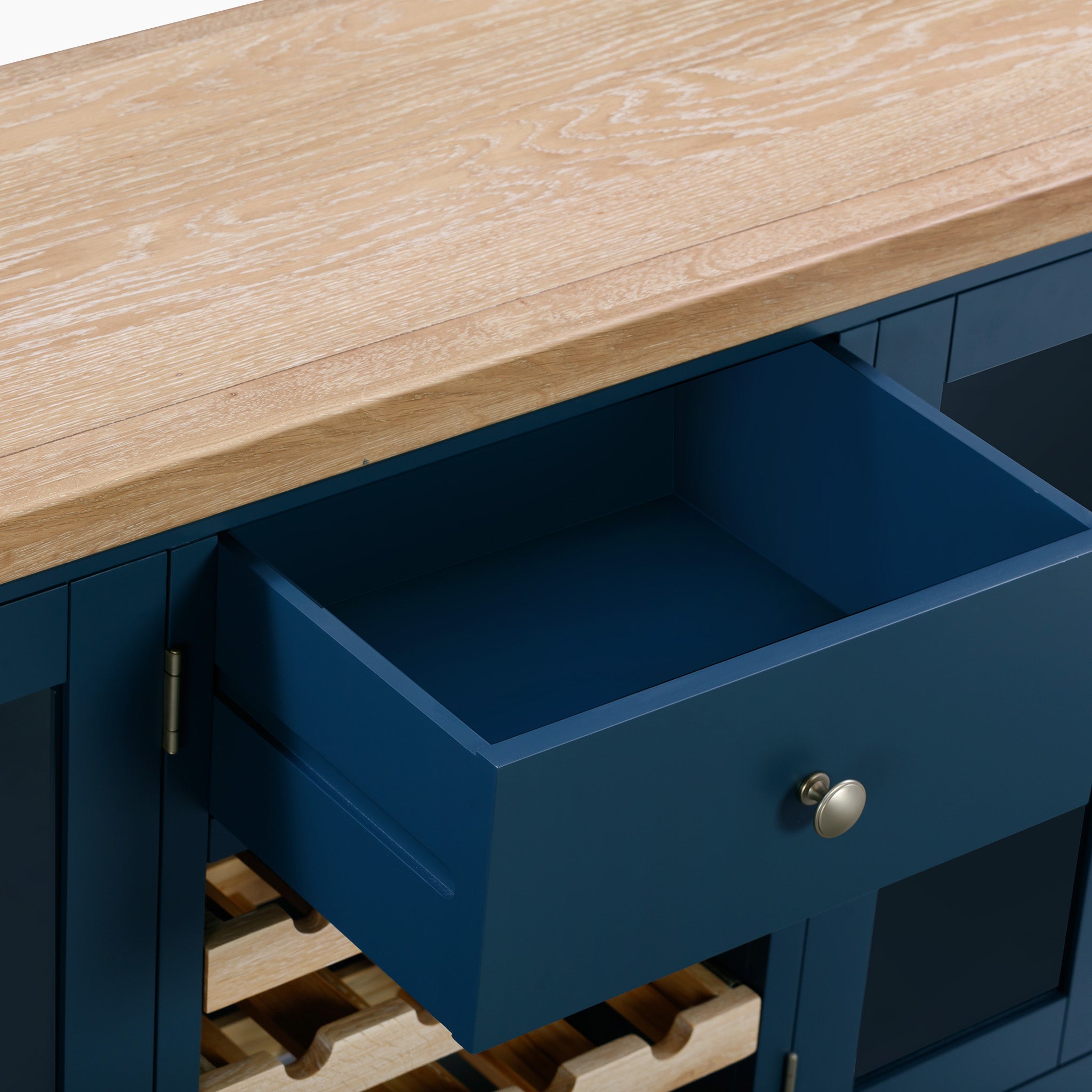 The Burford Grand Sideboard with Wine Rack in Navy Blue features a natural wood top and an open drawer, elegantly highlighting the oak wine rack underneath.