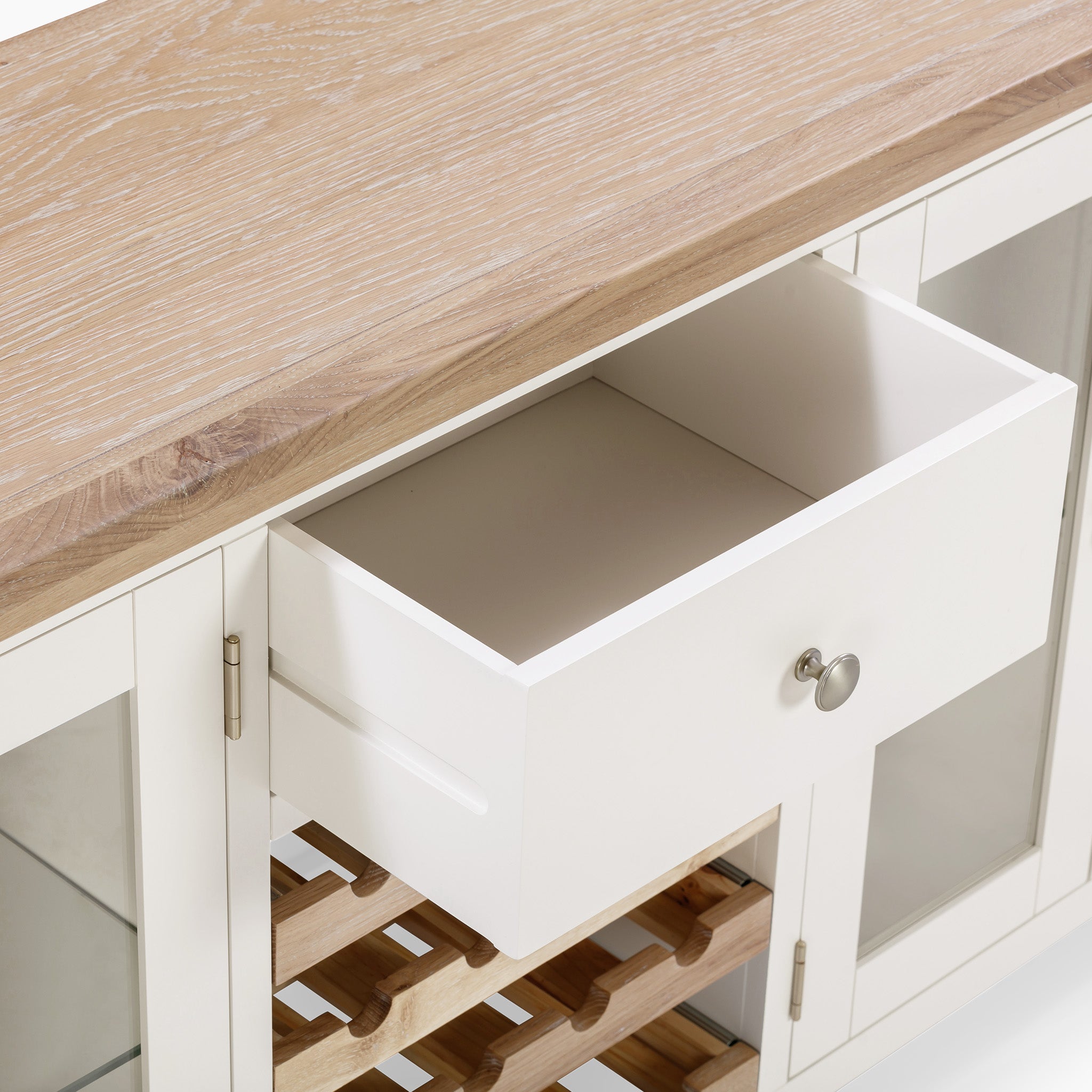 The Burford Grand Sideboard with Wine Rack in Warm White includes an open drawer, glass cabinet doors, and a sophisticated light wood top made from natural oak. Its elegant design is perfect for any dining room, seamlessly integrating a wine rack for enhanced functionality.