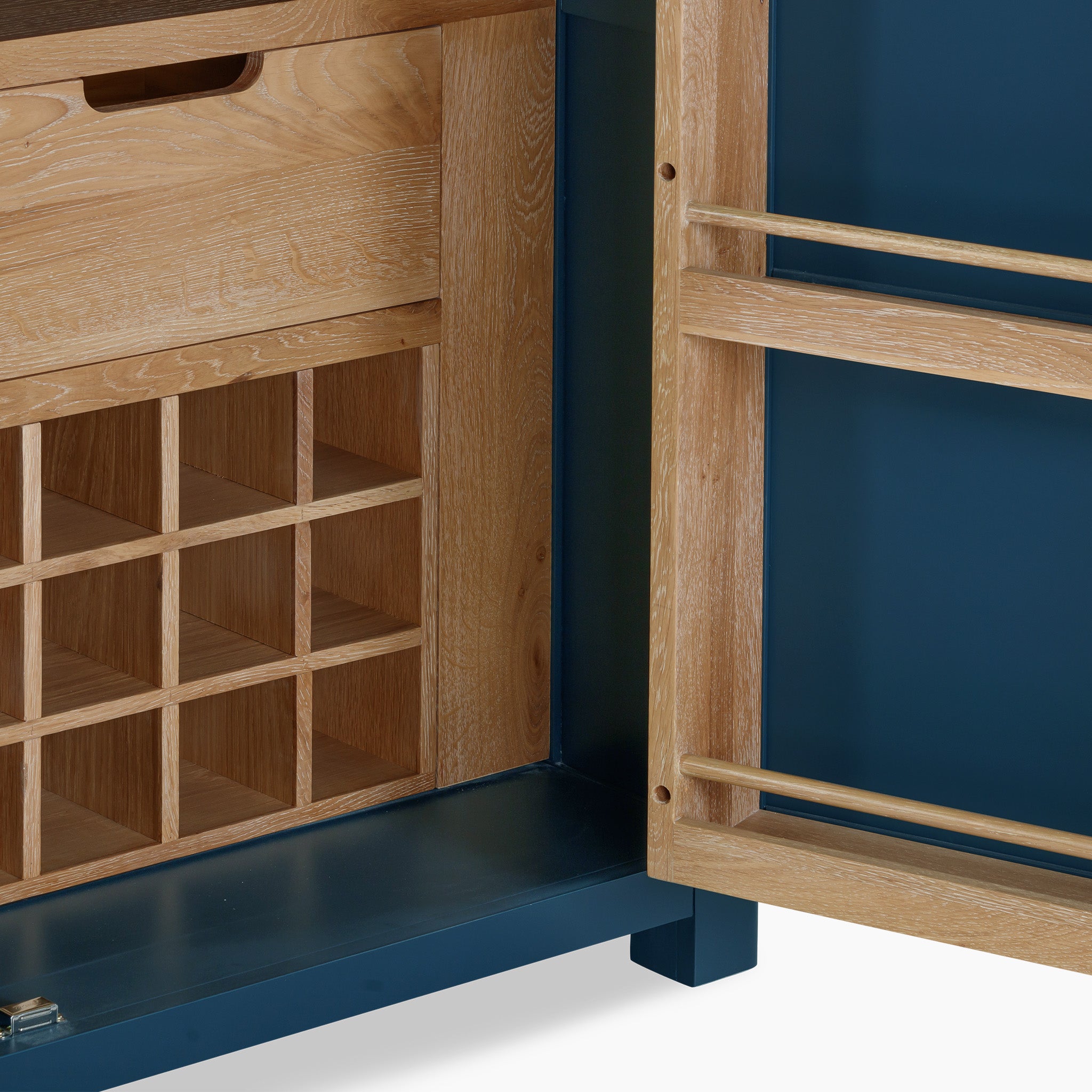 The Burford Single Larder Unit in navy blue is crafted from natural oak and features an open wooden cabinet with a wine rack, as well as a blue inside door fitted with two thin shelves, providing elegant kitchen storage.