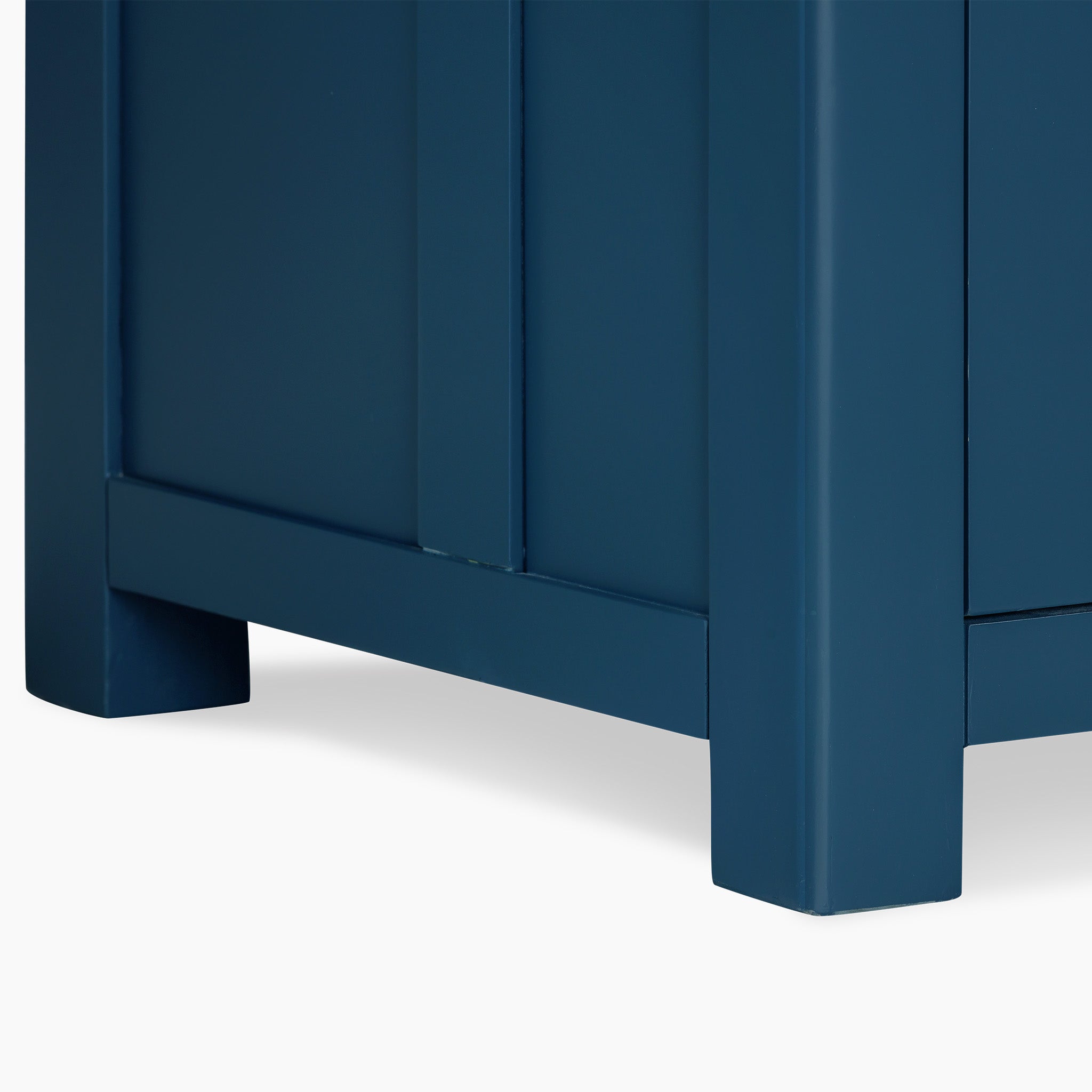 Close-up of a navy blue cabinet's corner featuring a modern, minimalist design, reminiscent of the elegant Burford Single Larder Unit in Navy Blue. Perfect for refined kitchen storage solutions, this piece seamlessly integrates natural oak accents for added warmth and sophistication.