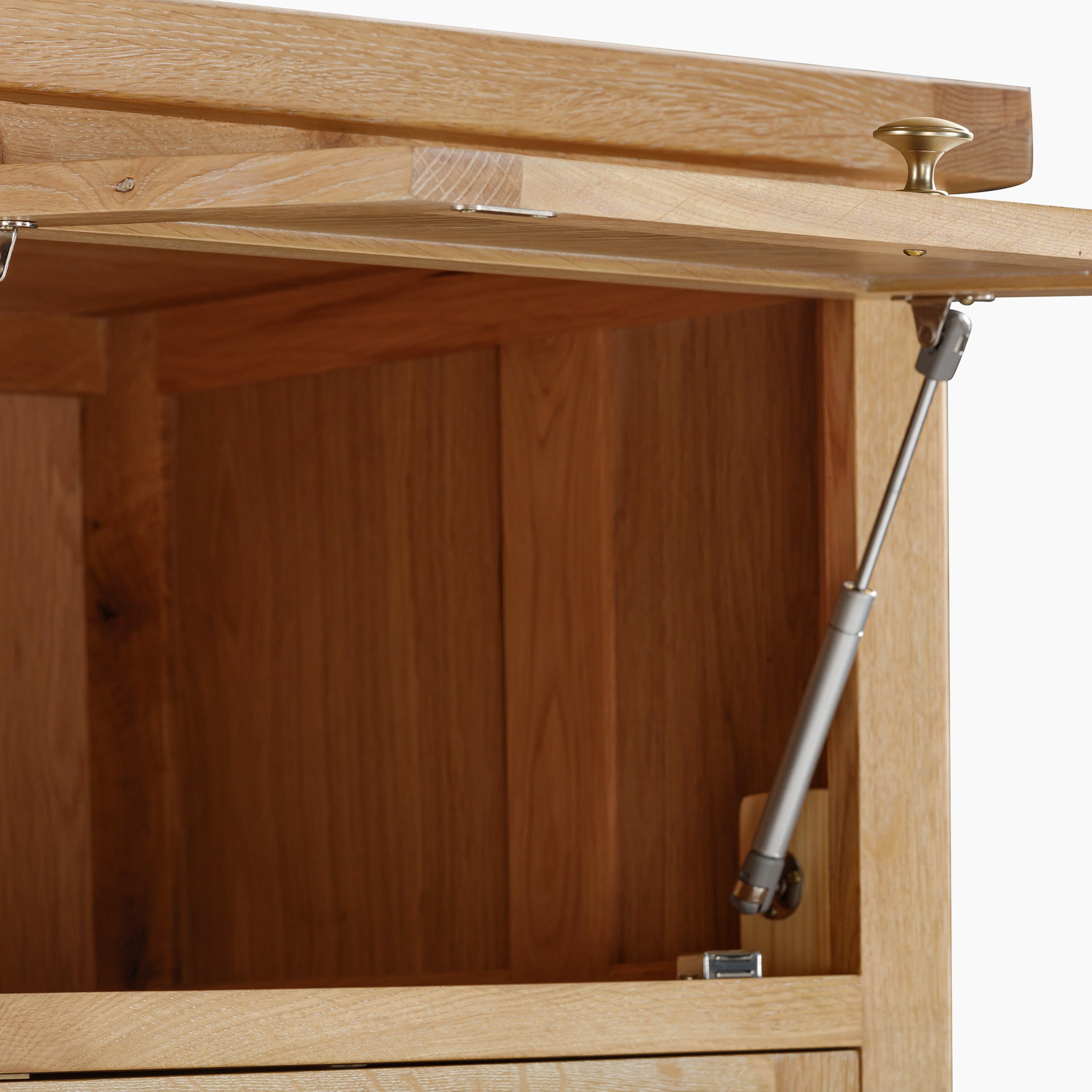 The Burford Single Larder Unit in Natural Oak features an open lid that reveals a hydraulic hinge mechanism and brass handle, making it perfect for smart storage solutions. Combining elegance and functionality seamlessly, it's the ideal choice for a larder unit.