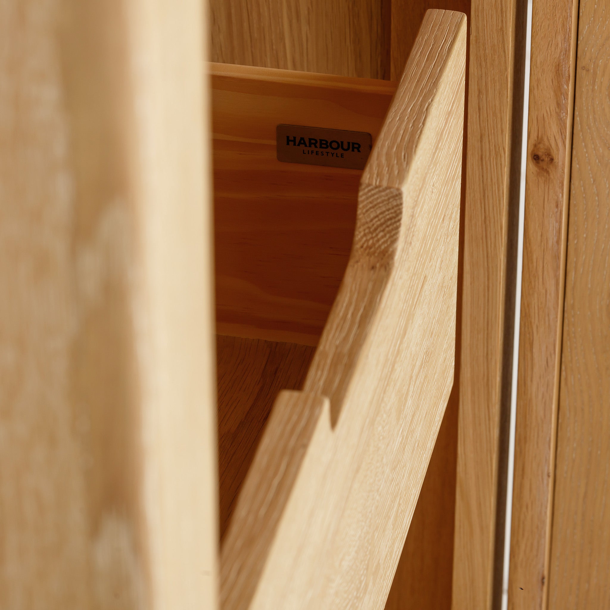 Open the drawer of the Burford Single Larder Unit in Natural Oak, revealing a smart storage solution. Sunlight highlights the natural oak grain, adding a touch of elegance to this exquisite piece.