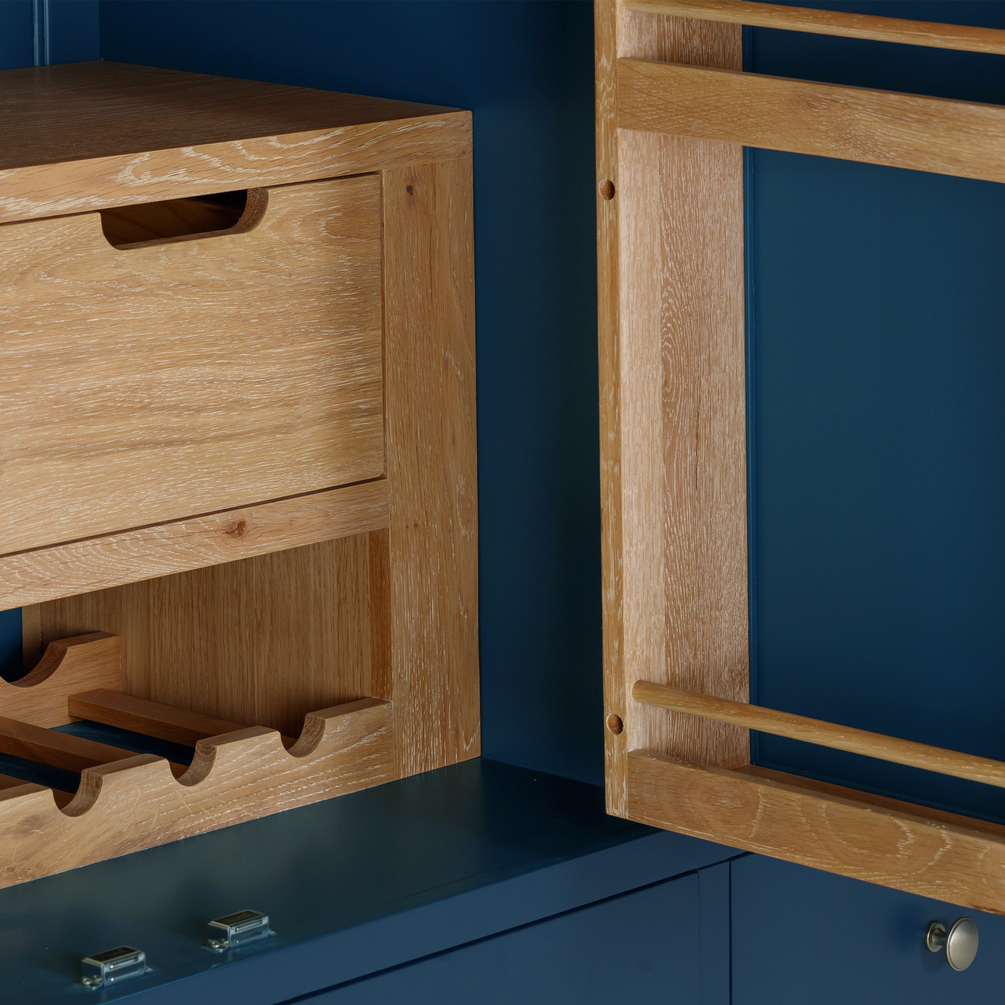 The Burford Triple Larder Unit in Navy Blue, with its elegant wooden cabinets that feature a wine rack and drawer, is beautifully enhanced by a solid oak top against the navy blue backdrop. This sophisticated setup exudes charm and elegance.