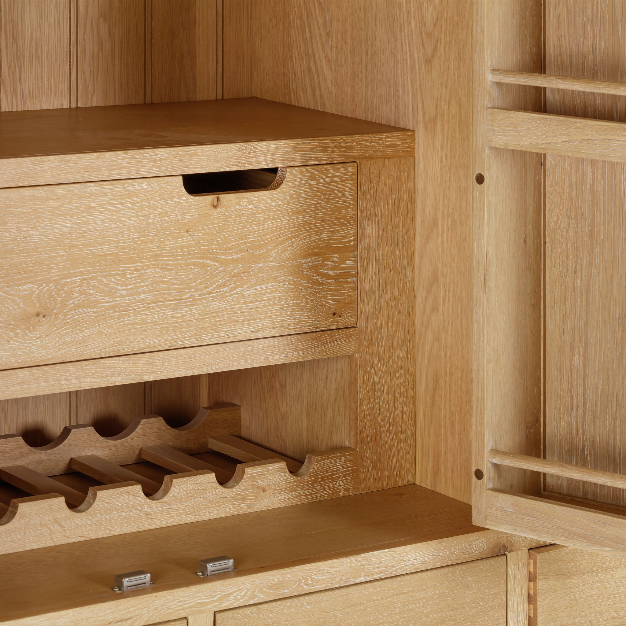 The Burford Triple Larder Unit in Natural Oak is an exquisite wooden cabinet that features an open drawer and a wine rack. Its light grain texture and built-in shelving make it a perfect kitchen storage solution.