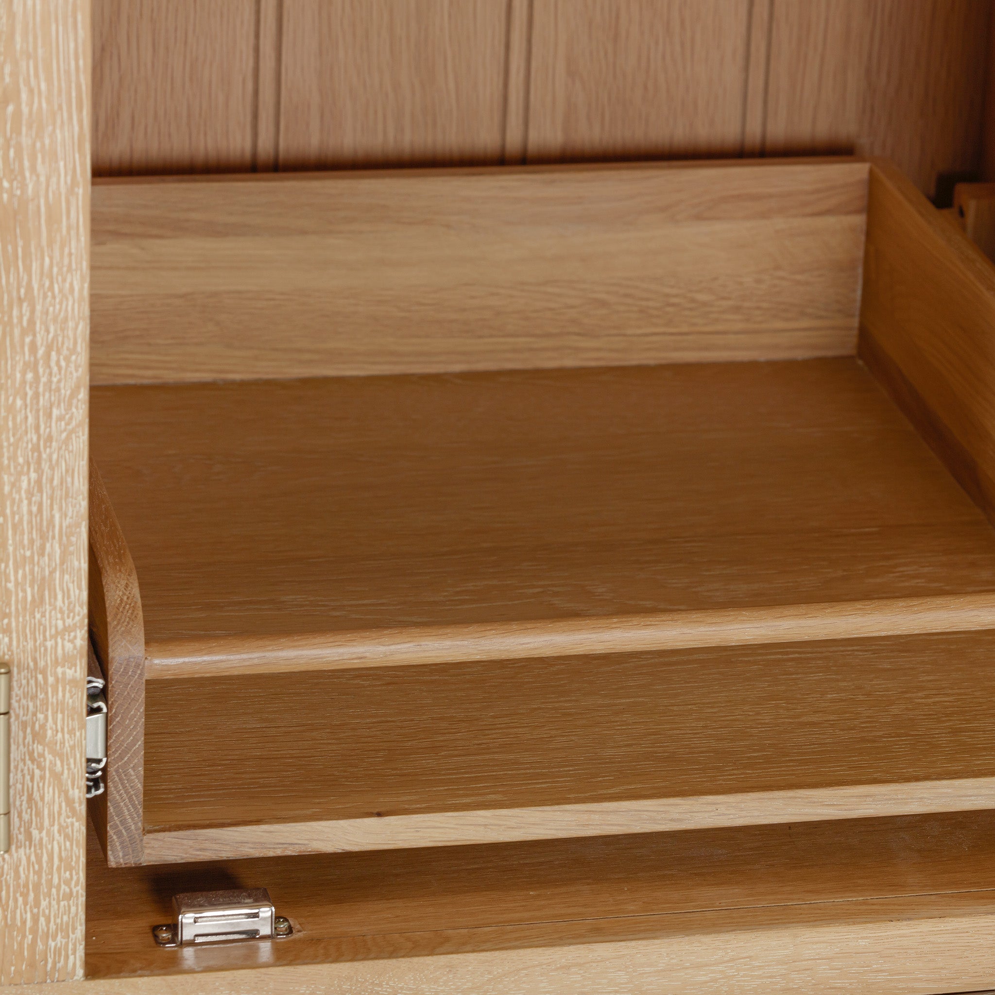 The Burford Triple Larder Unit in Natural Oak features an empty wooden drawer and a visible hinge on the side, providing practical storage for your kitchen.