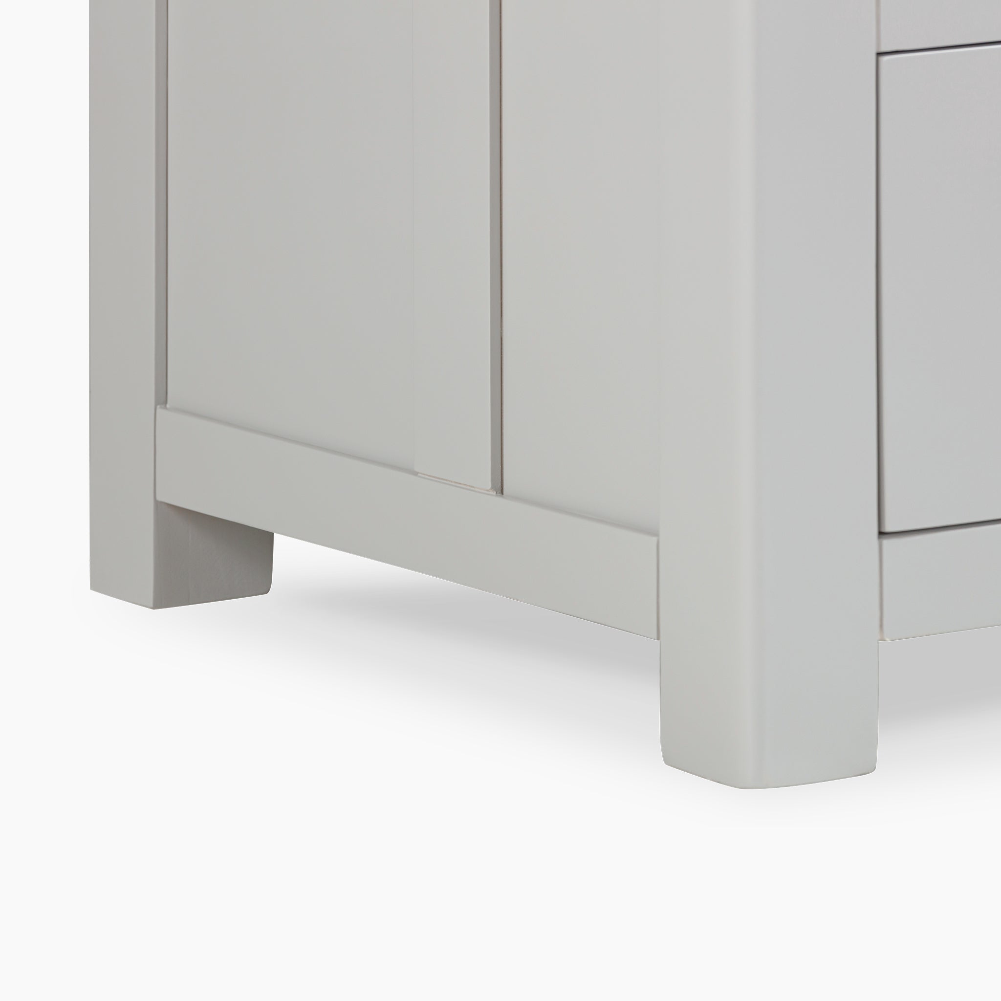 Close-up of a pebble grey cabinet corner revealing a door and drawer, epitomizing elegant kitchen storage solutions on a pristine white background with the Burford Triple Larder Unit.