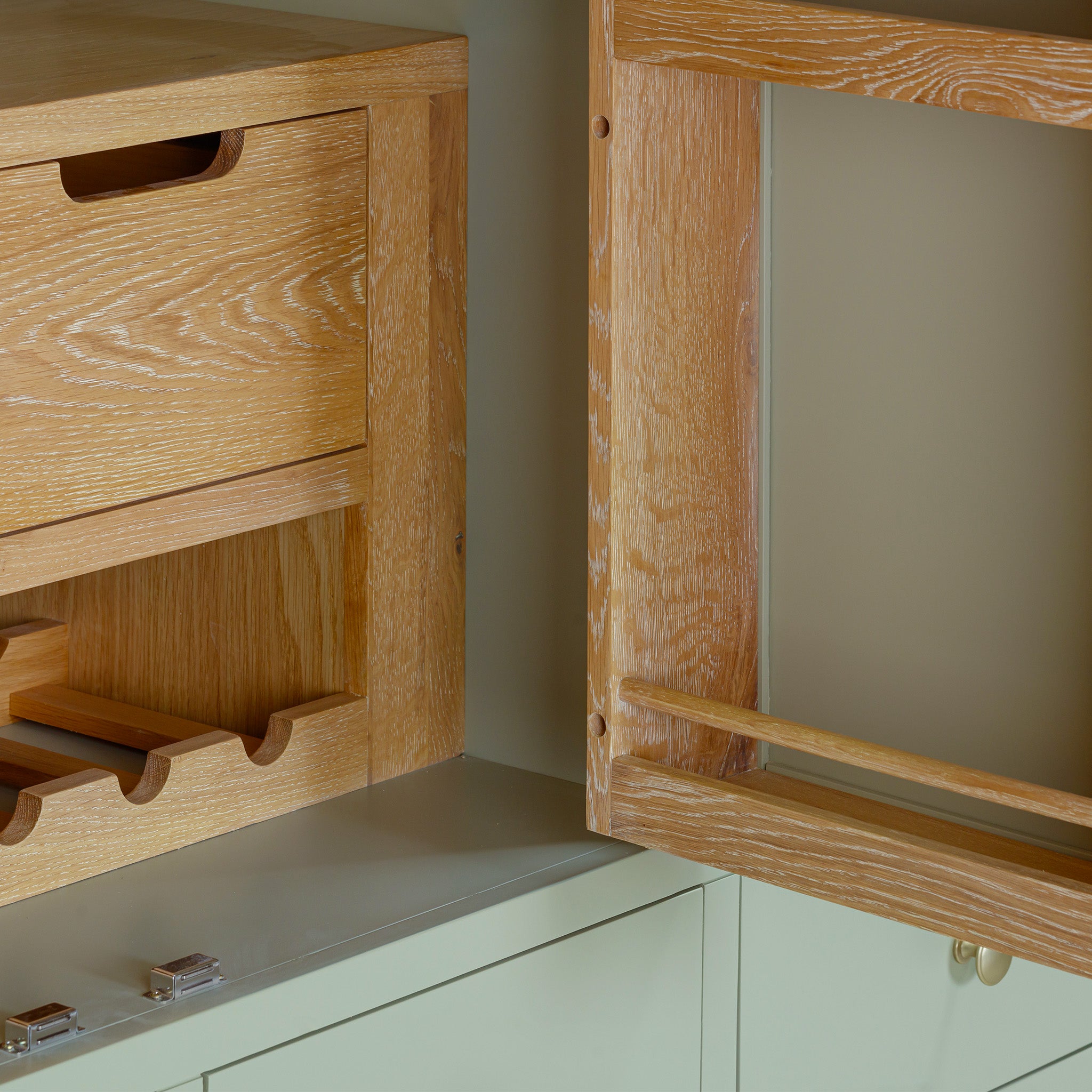 Close-up of wooden kitchen cabinets and drawers with a light wood finish on a beige background, perfectly complementing the elegant Burford Triple Larder Unit in Sage Green nearby.