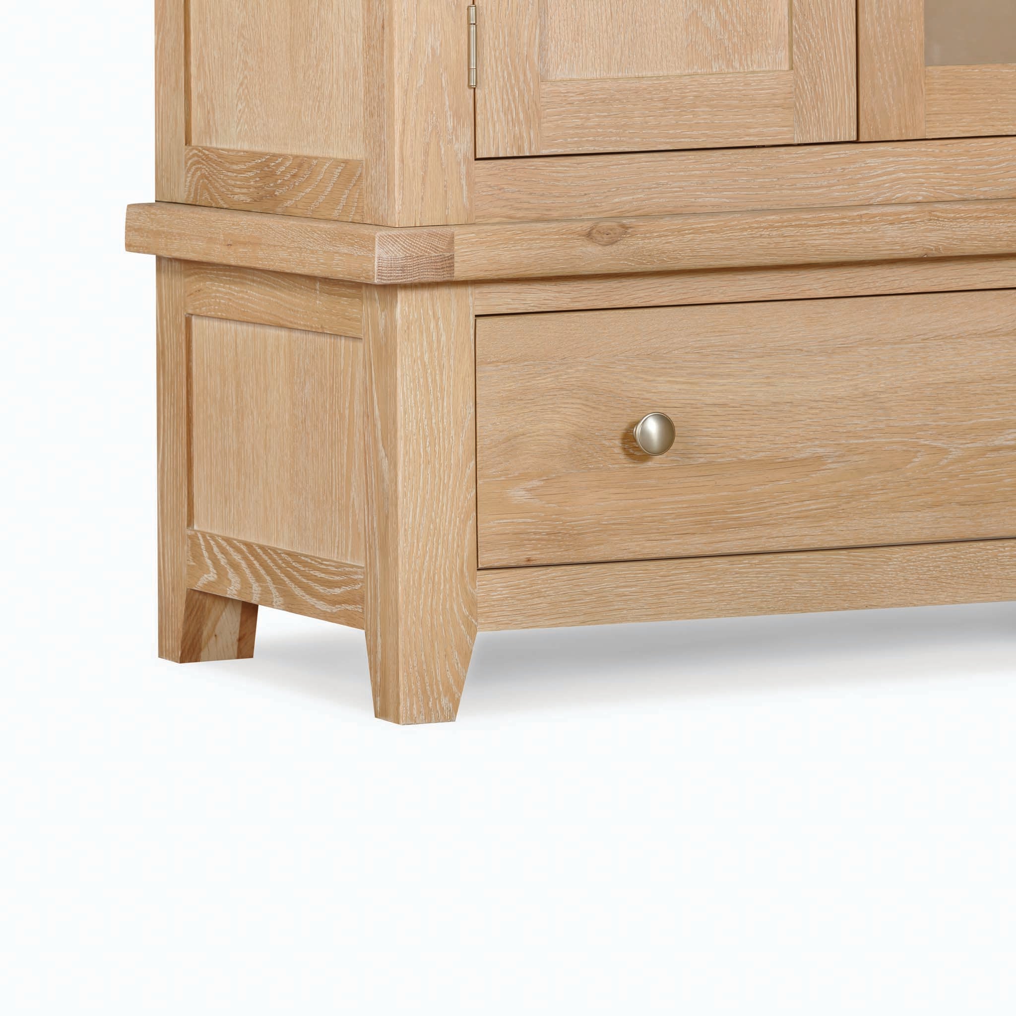 Close-up of the corner of a light wooden Burford Triple Wardrobe with 2 Drawers in Natural Oak, featuring a brass knob on a drawer, showcasing clean lines and detailed wood grain—a perfect natural oak storage solution.