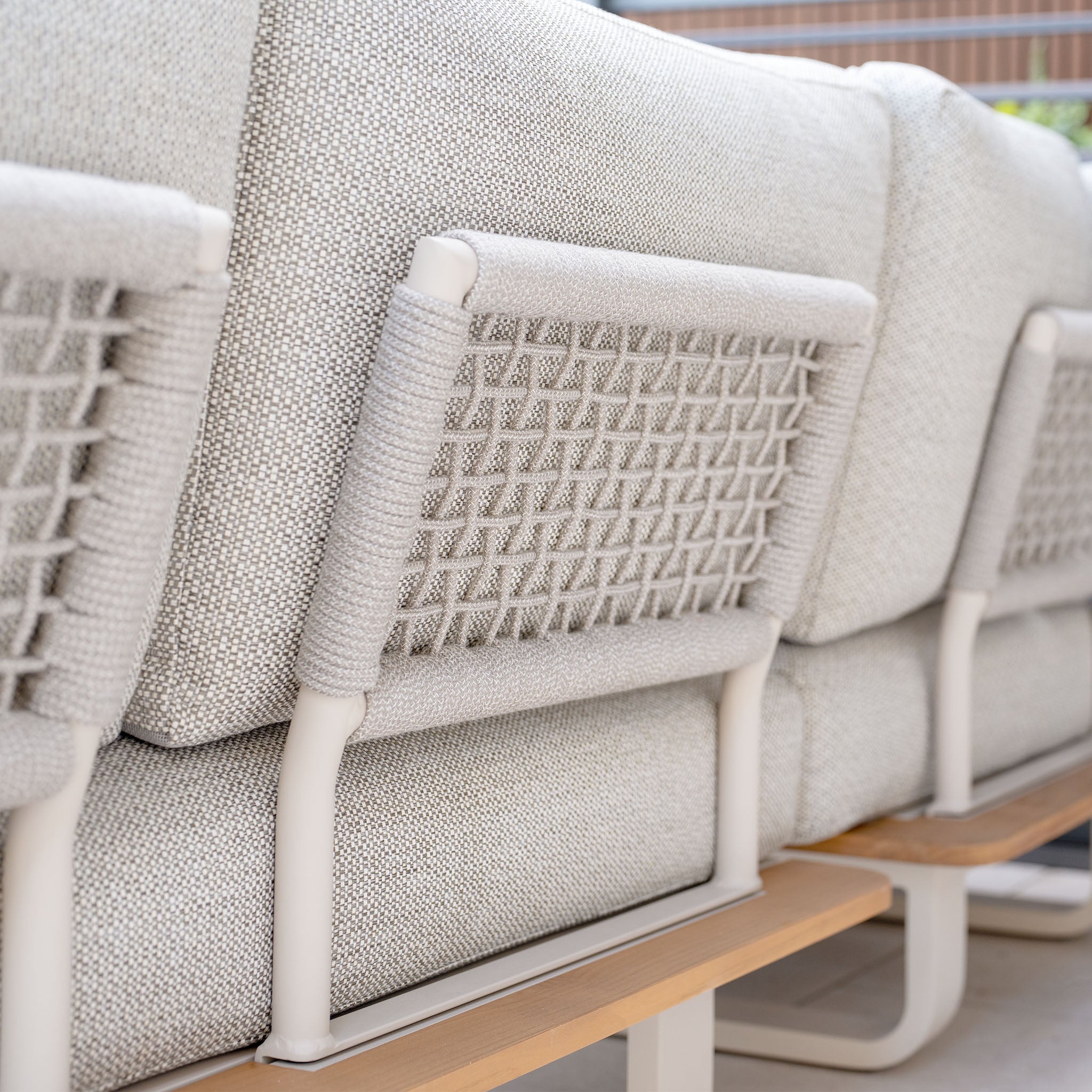 Close-up of the back of the Bay Corner Group Set with its 4 Waist Pillows and Teak Table in Latte, featuring a gray textured outdoor sofa with woven accents and a powder-coated aluminium frame, showcasing the durability of Olefin material.