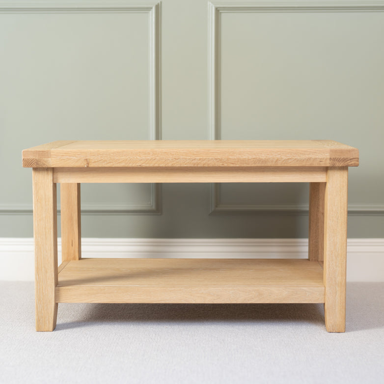 The Burford Large Coffee Table with Shelf in Natural Oak stands against a muted green paneled wall.