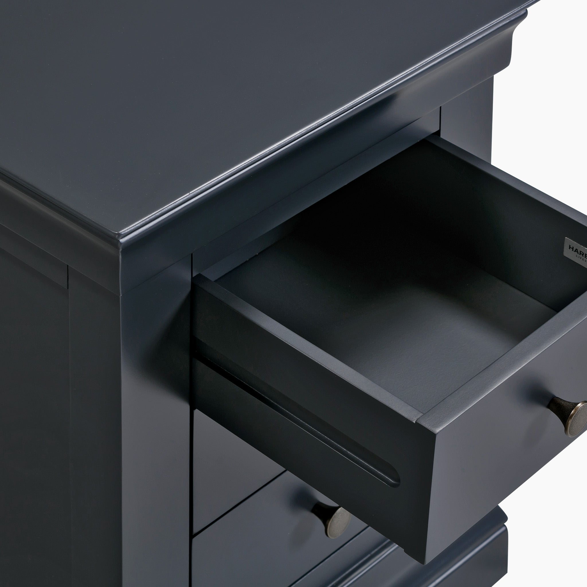 The Chalbury 3 Drawer Bedside Table in Dusky Black showcases a dark gray drawer unit, elegantly designed with one drawer open to reveal its smooth, modern aesthetic. Its sophisticated look is further enhanced by the subtle solid oak finish, making it a chic addition to any bedroom.