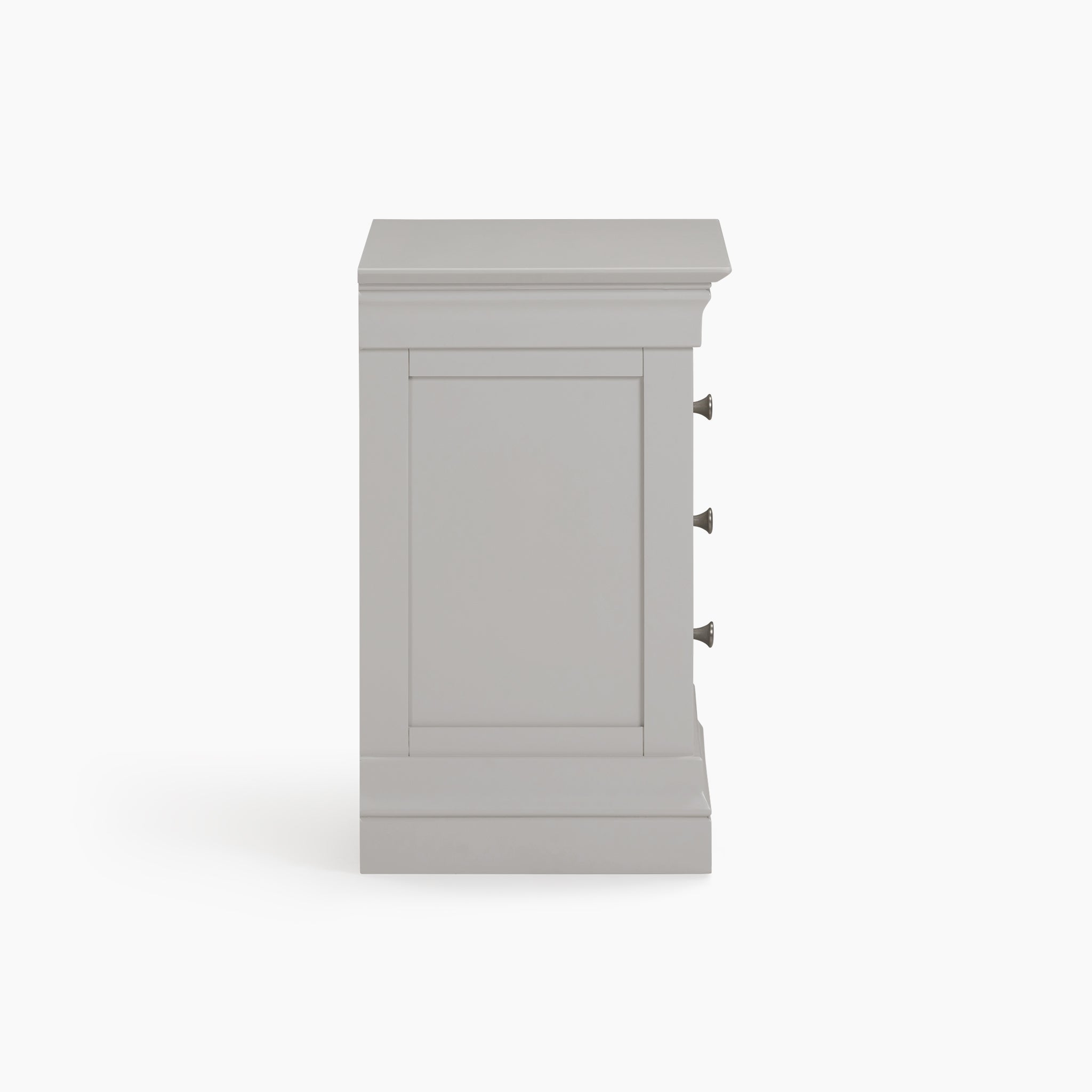 The Chalbury 3 Drawer Bedside Table, finished in sophisticated Pebble Grey, is shown from a side angle with its three drawer handles prominently displayed against a white backdrop.