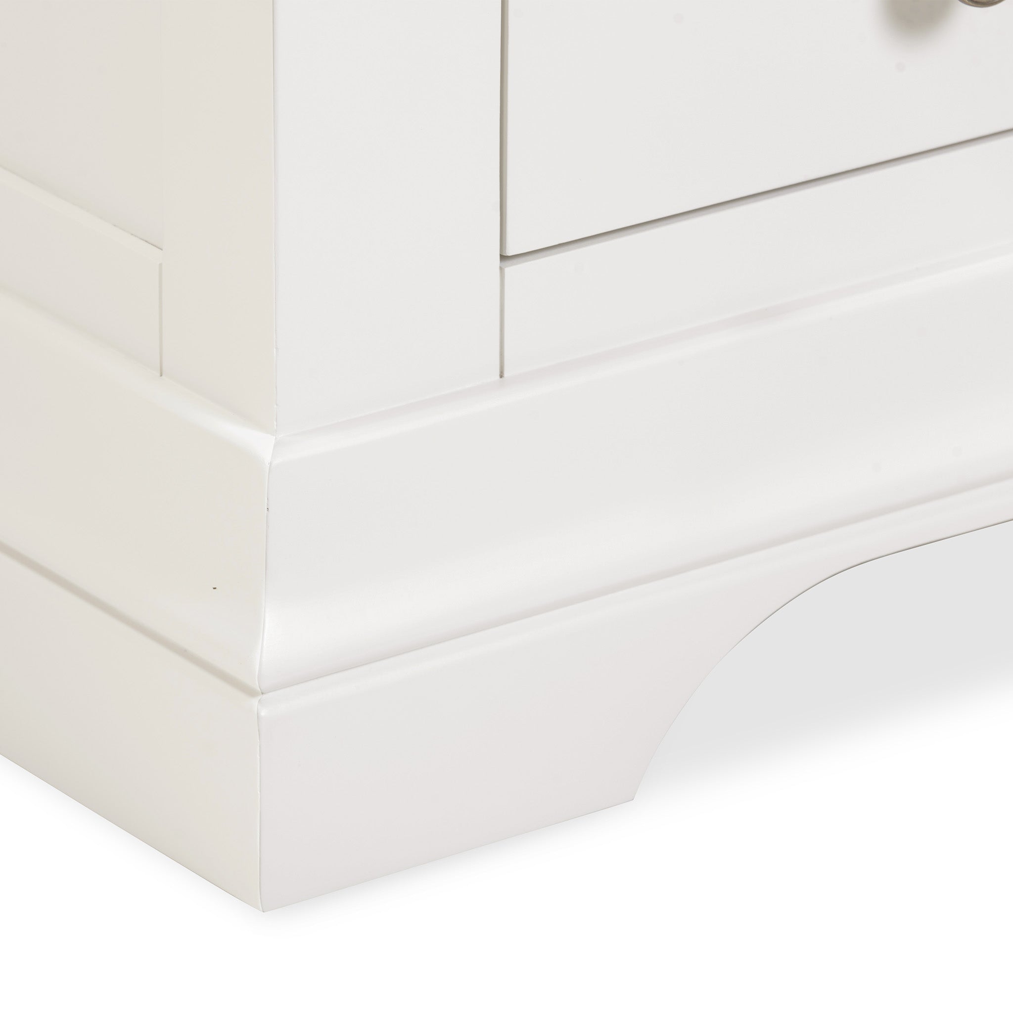 Close-up of the Chalbury 3 Drawer Bedside Table in Warm White, highlighting the elegantly curved cutout baseboard and drawer edges of this white dresser that seamlessly blend into any bedroom décor.