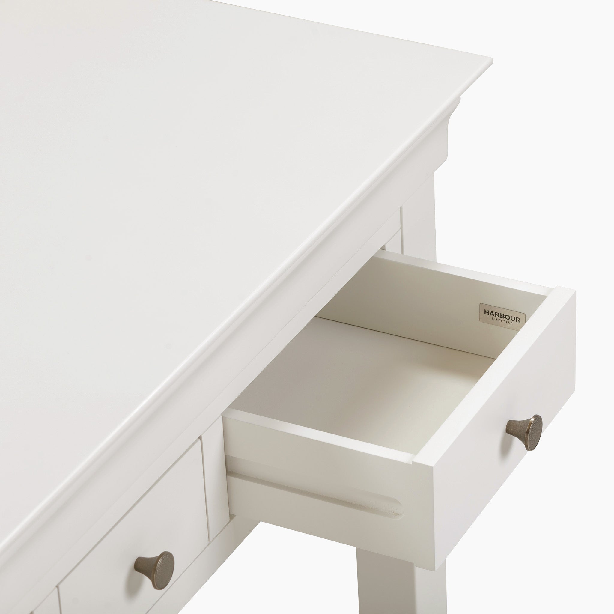 The Chalbury Console Desk in Warm White exudes modern elegance with its white wooden table, open drawer highlighting a minimalist design, and sleek metal handles.