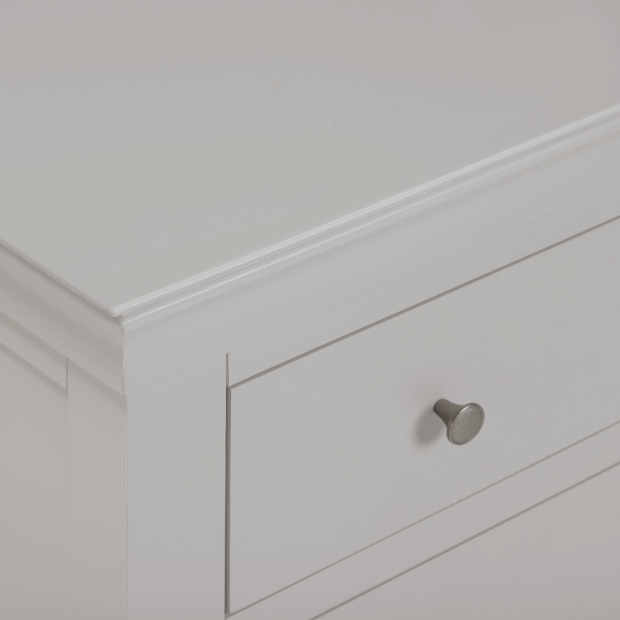 Close-up of the Chalbury 2 Over 3 Chest of Drawers in Pebble Grey, showcasing a corner with a single drawer that features a round metal knob.