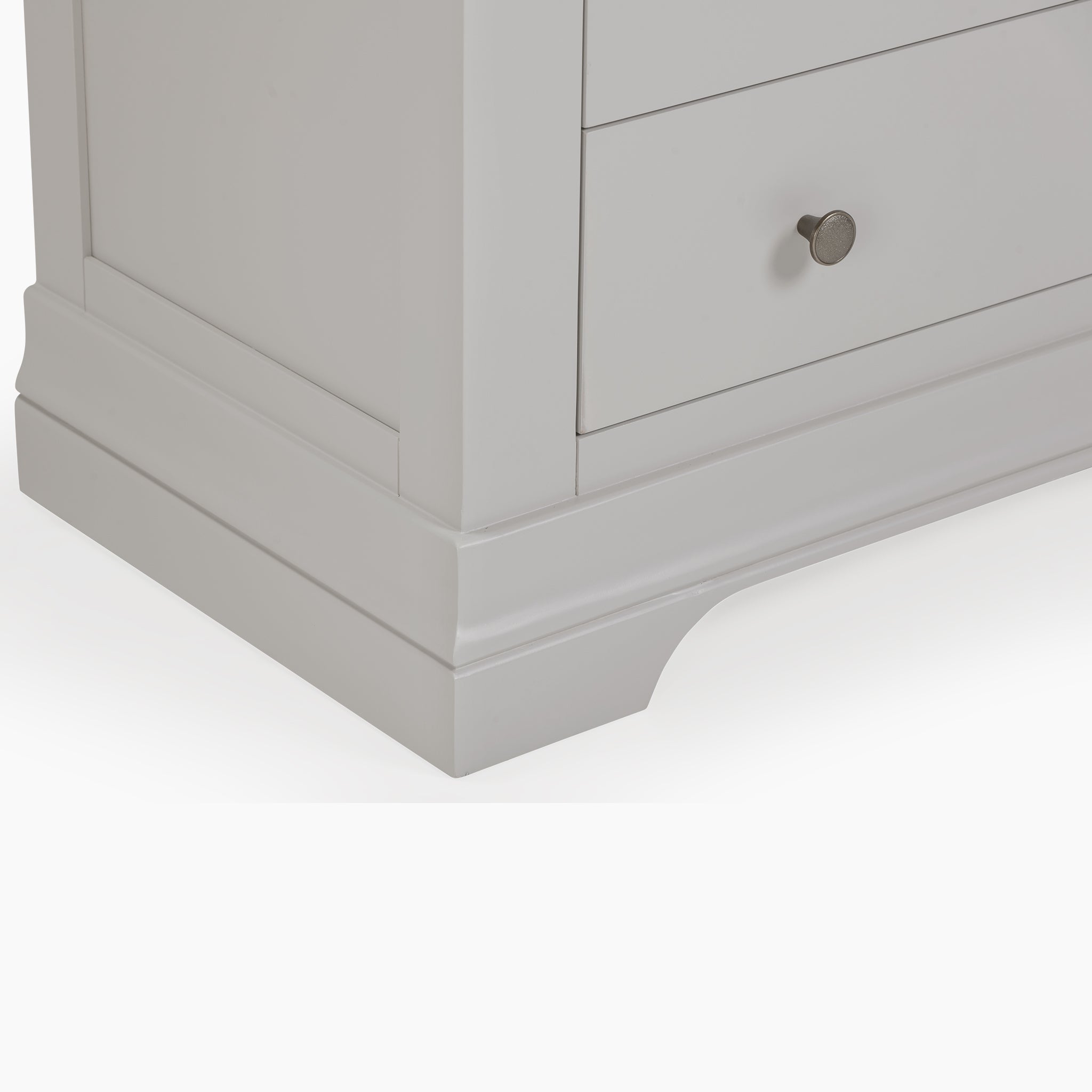 Close-up of a Pebble Grey cabinet corner with a drawer featuring a round metal knob, reminiscent of the elegant design of the Chalbury 3 Drawer Chest in Pebble Grey.