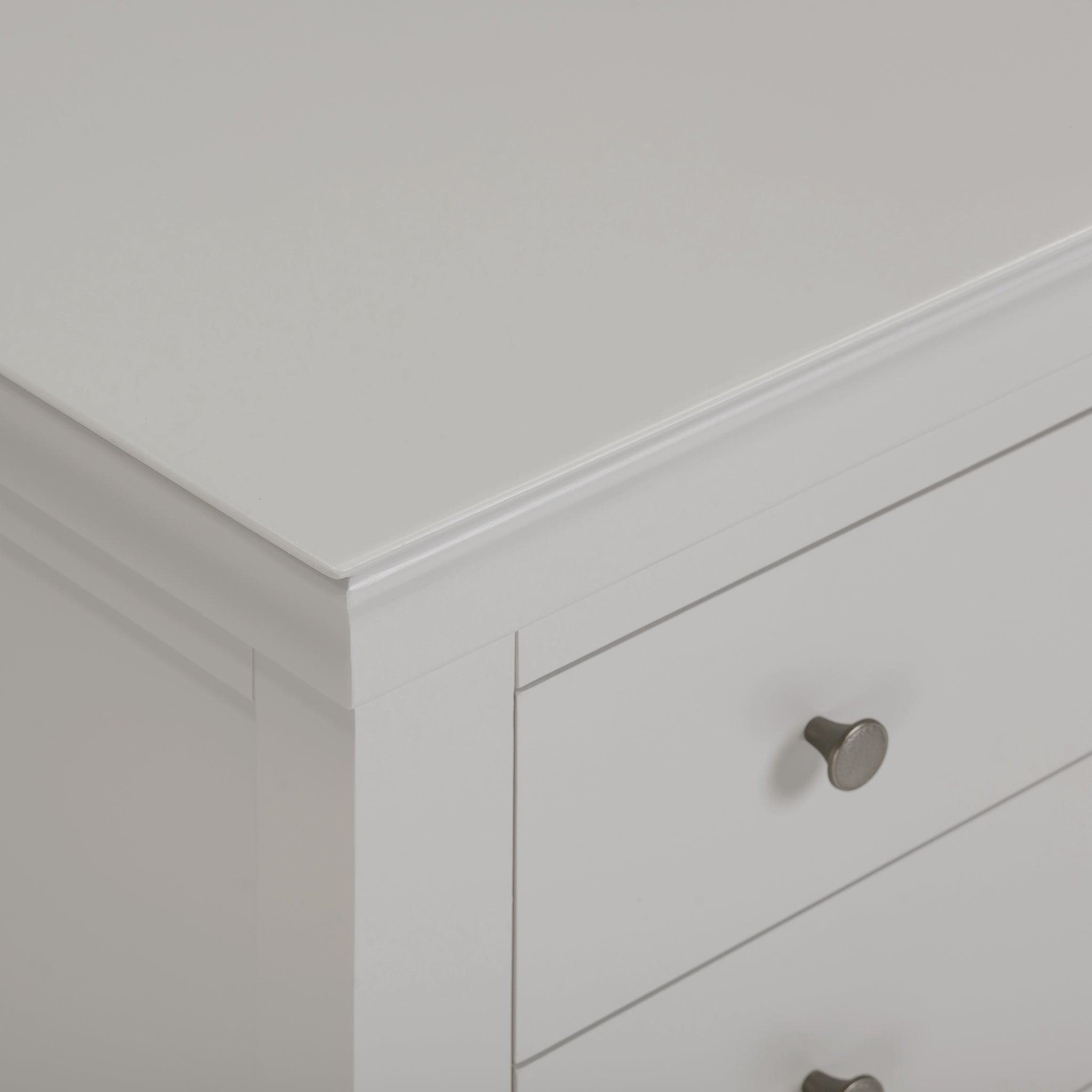 A close-up of the Chalbury 3 Drawer Chest in Pebble Grey showcases its metallic round knobs, making this elegant storage furniture an ideal addition to elevate any room with sophistication.