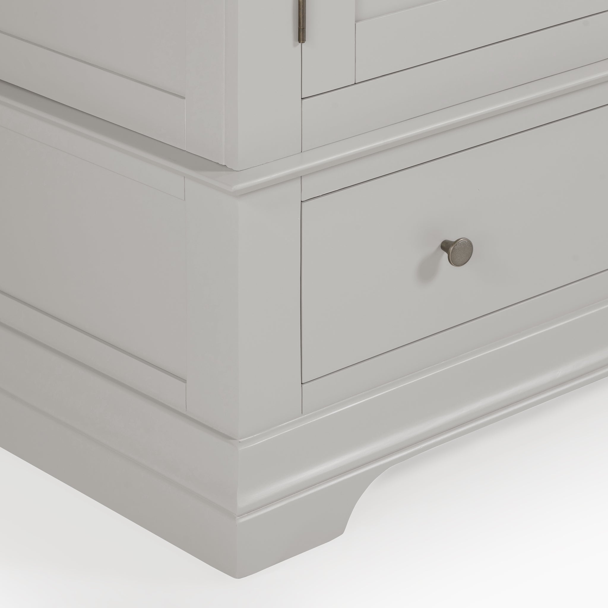 Close-up of a Pebble Grey cabinet corner featuring a drawer with a metal knob against a white background, enhancing the spacious storage of the Chalbury Double Wardrobe in Pebble Grey.