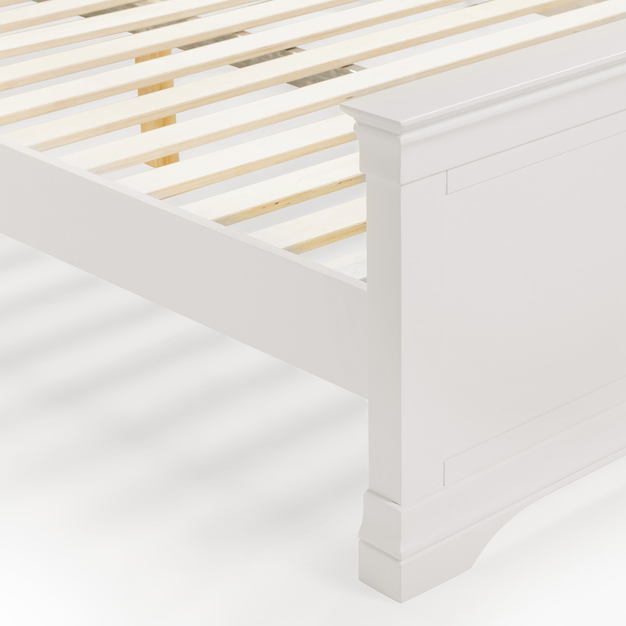 The Chalbury 4ft 6" High End Double Bed Frame in Warm White, featuring a slatted base and decorative corners, exudes luxury with its angled side view.