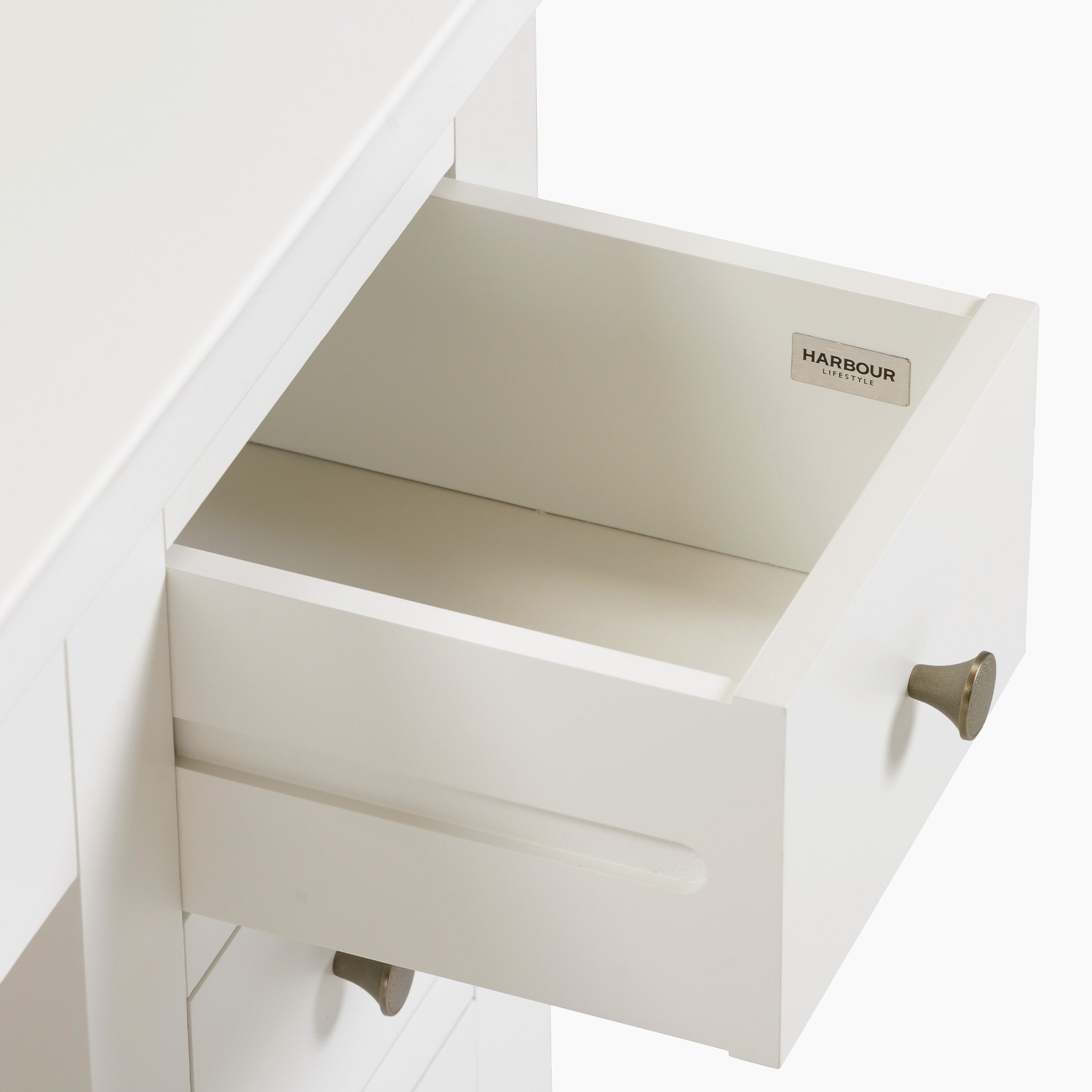 The Chalbury Dressing Table with Drawers in Warm White features a partially open drawer adorned with sleek metal handles and a petite "Harbour" label inside.