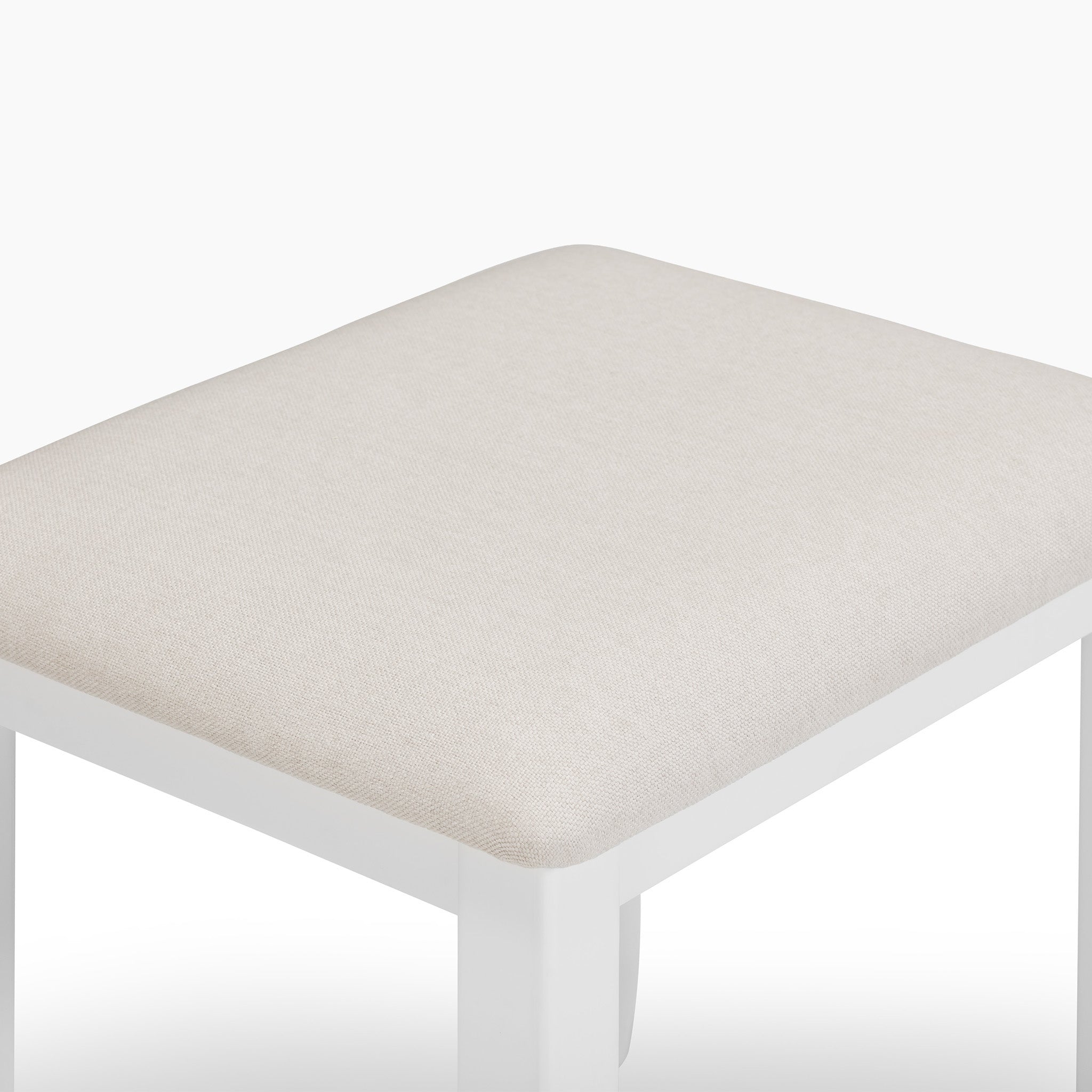 The Chalbury Stool in Warm White showcases a sleek design in a warm white hue, complemented by a built-in beige cushion, creating an elegant contrast against its pristine background.