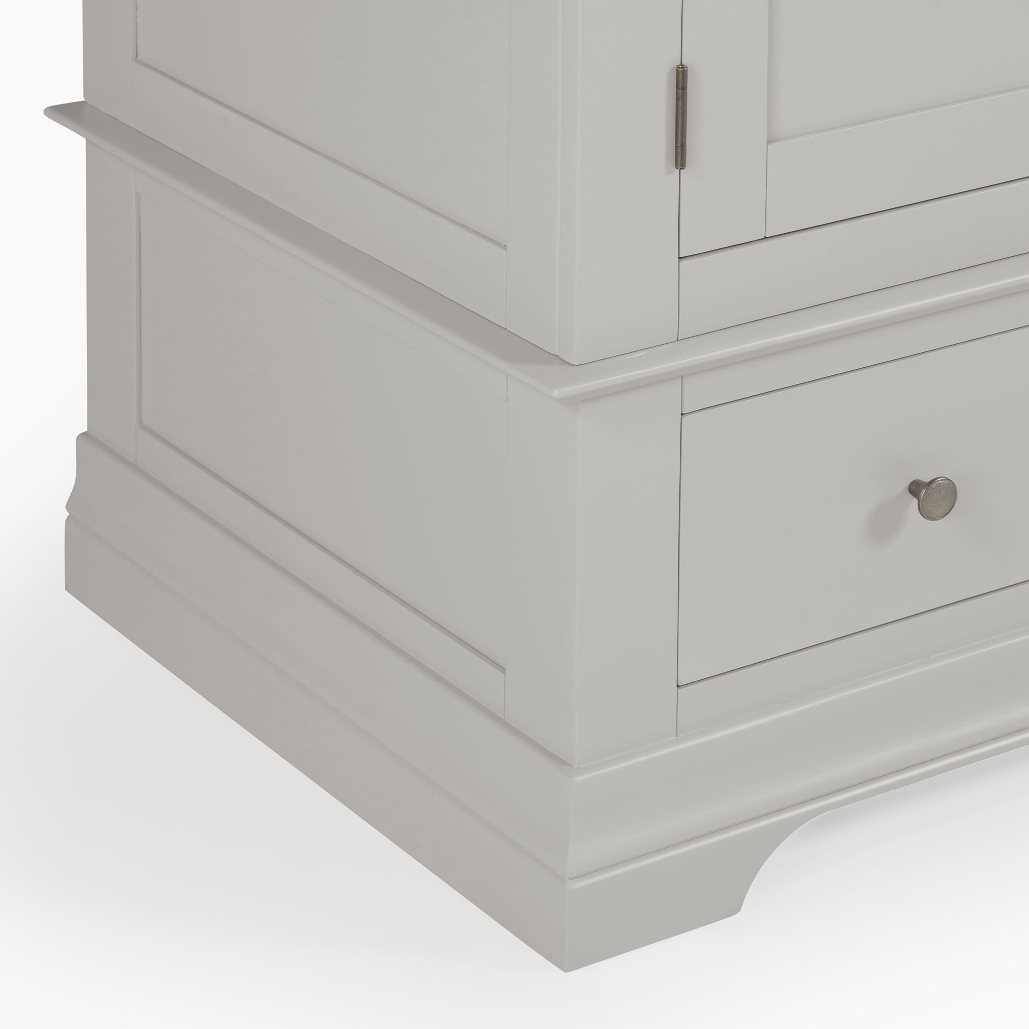 Close-up of the lower section of a Chalbury Triple Wardrobe in Pebble Grey, featuring a drawer and a door with a round metallic knob.